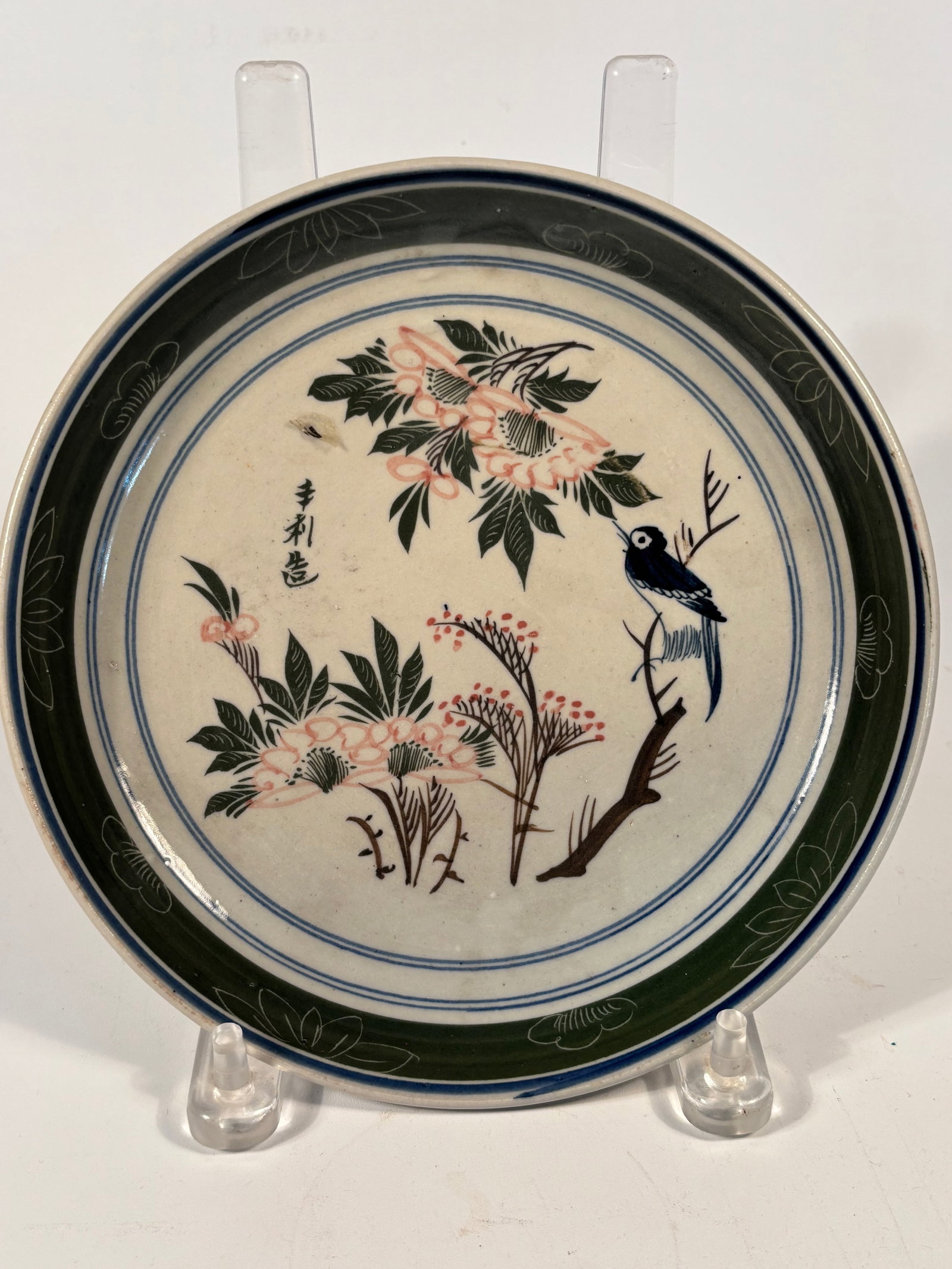 An Asian porcleain brush washer dish: 18th-19th Century; hand-painted with a graceful scene of a bird perched on a flowering branch, surrounded by finely rendered foliage. Executed in a restrained palette of black, soft pink, and green, t