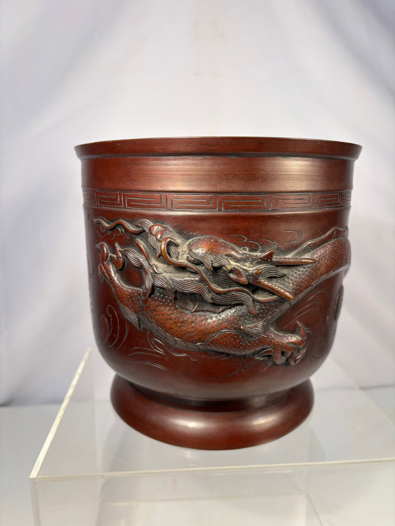 A Japanese Bronze Dragon Incense Burner with Workshop Seal, Meiji Period: Meiji period (1868–1912), Cast bronze incense burner of deep bowl form, decorated in high relief with a striding dragon amid scrolling clouds, the body with a key-fret border below the rim, raised o
