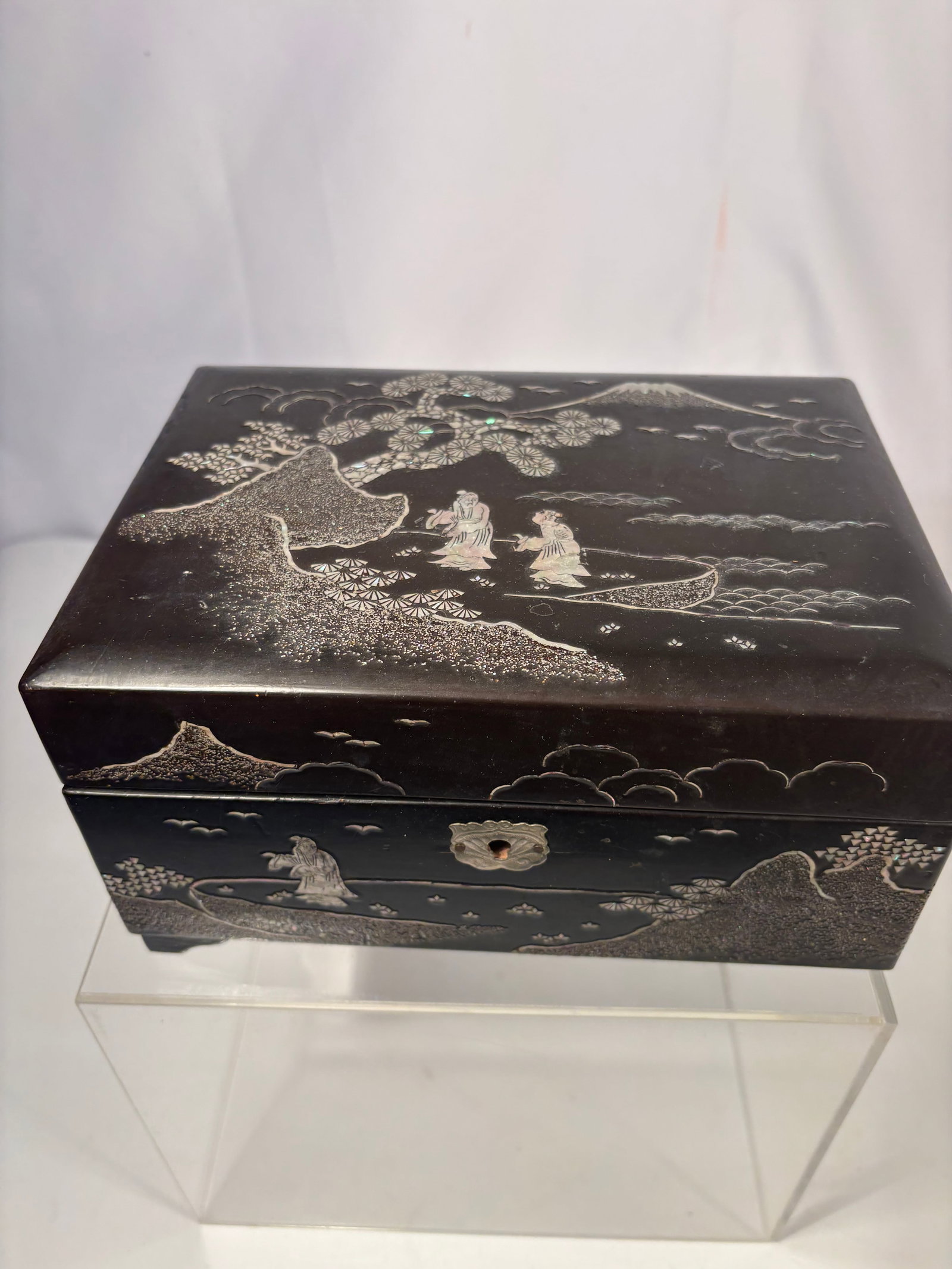 A Japanese Black Lacquer Mother-of-Pearl Inlaid Musical Jewelry Box with Mount Fuji Scene: A vintage Japanese black lacquer musical jewelry box, decorated with shimmering mother-of-pearl inlay depicting Mount Fuji, pine tree, clouds, and figures in a boat. The hinged lid opens to a blue vel
