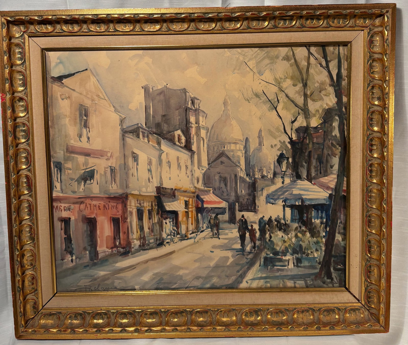 Lucien Delarue (French 1925–2011) Paris Montmartre Street Scene Watercolor: Original watercolor and gouache on paper by Lucien Delarue depicting a romantic Parisian Montmartre street scene with café façades, strolling figures, and the dome of Sacré-Cœur emerging through t