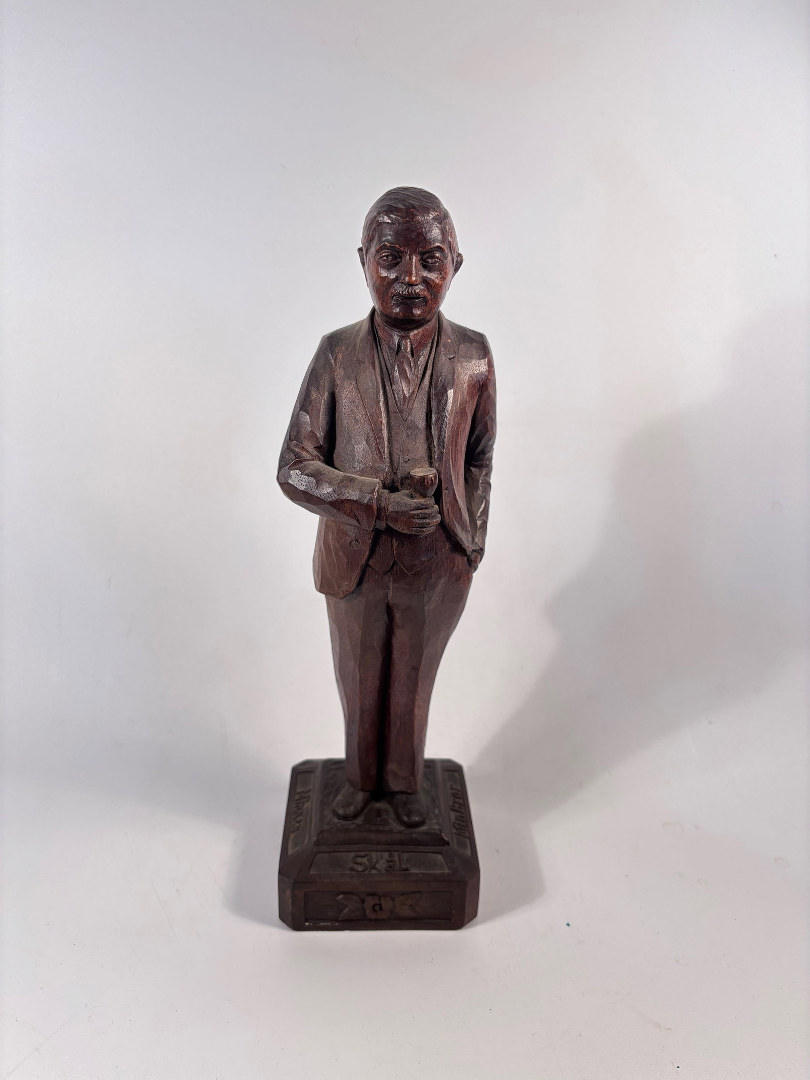Vintage Swedish Folk Art Carved Wood Figure – “Skål / Min Bror?? Commemorative Sculpture: A charming vintage Swedish folk art wood carving, depicting a gentleman in a suit with one hand raised in a toast. The figure stands confidently on a multi-tiered base with hand-carved inscriptions on