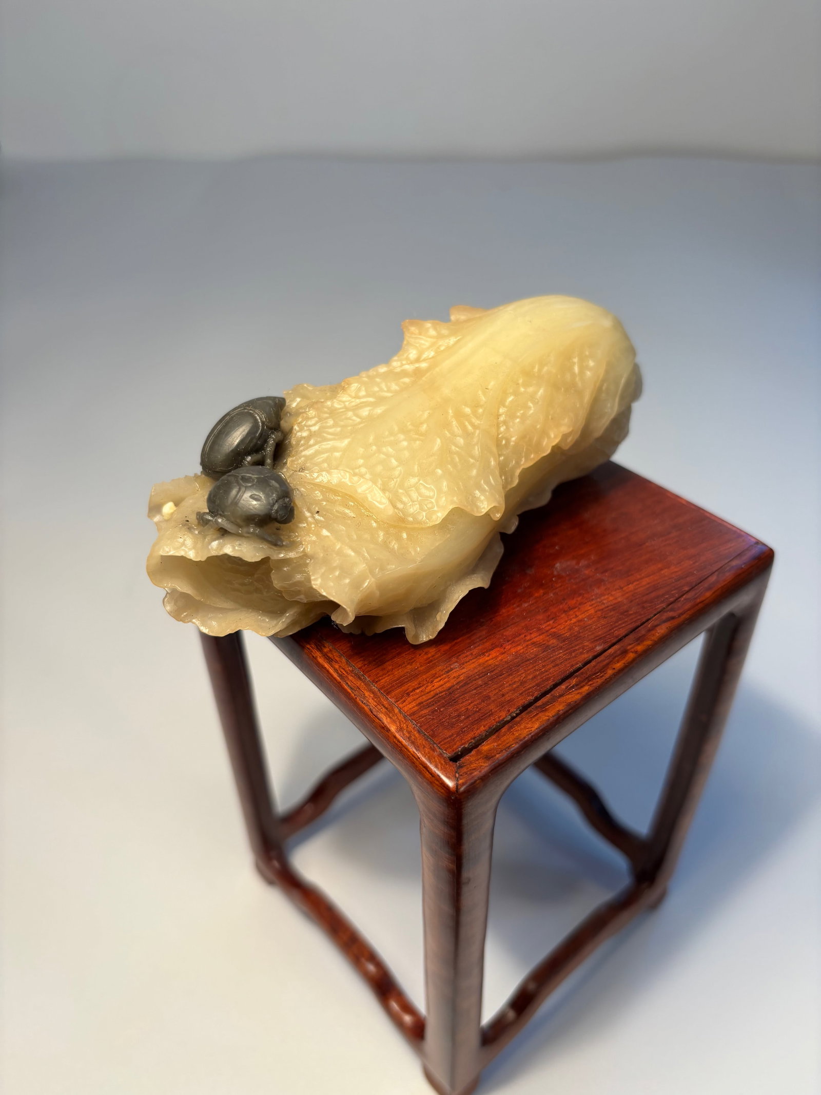 A Chinese hand carved jade carbbage with insects: Qing Dynasty (1644-1912); a jade carving of a bok choy (Chinese cabbage) with two black-colored insects or snails perched on it. Dimensions?Length:4.25 inches