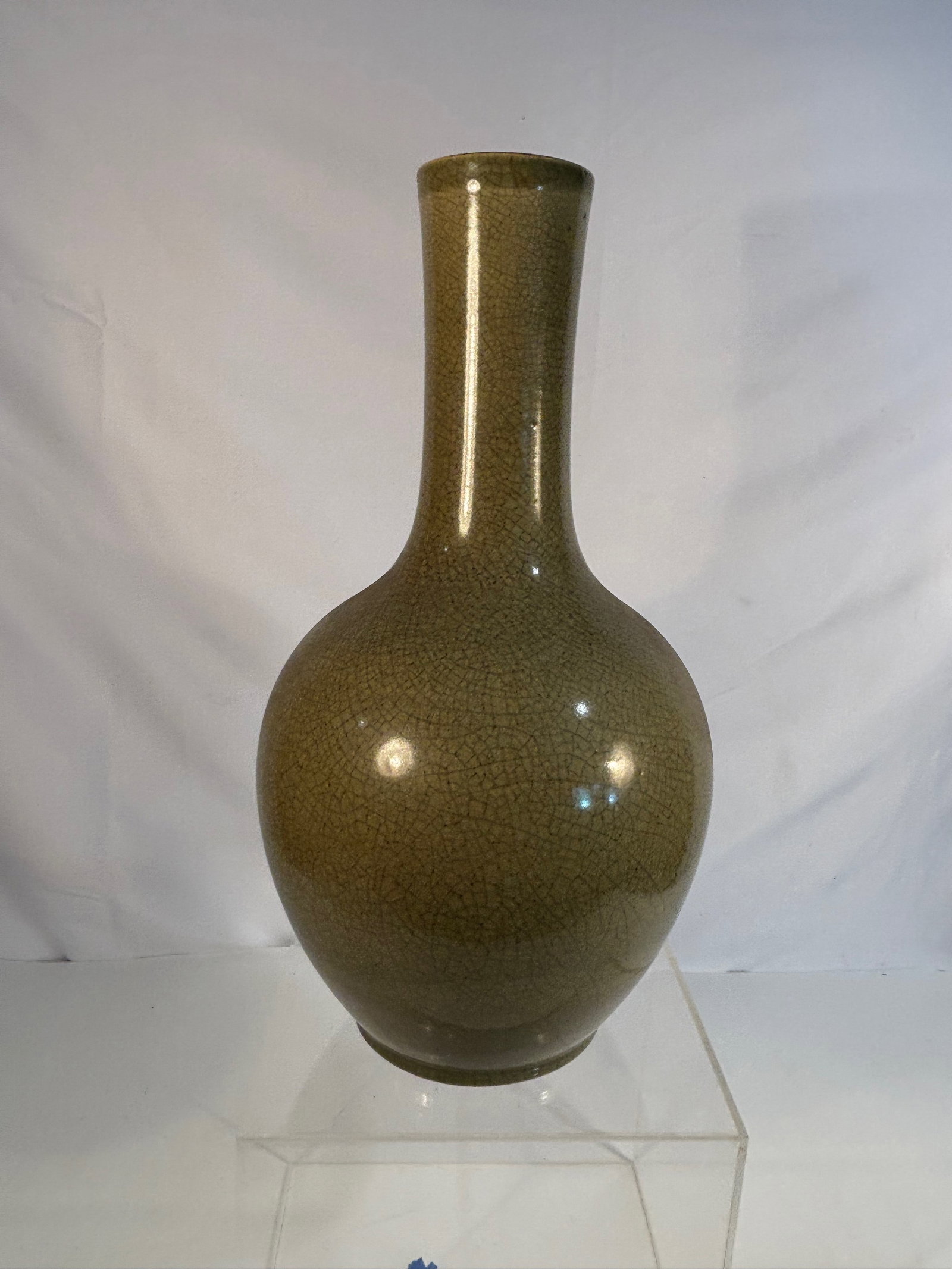 A Chinese Celadon Crackle-Glazed Porcelain Vase: 19th-20th century, Chinese celadon crackle-glazed vase, with olive-green glaze suffused with an overall network of fine crackles, long neck and rounded body, in the style of Song. Dimensions?Height: 1