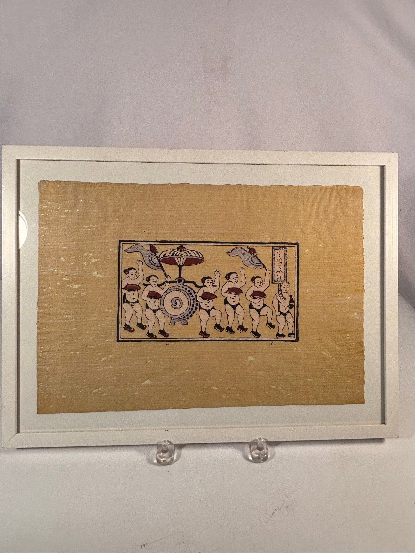 Japanese Folk Woodblock Print of Festival Dancers, Framed: A Japanese folk woodblock print depicting a lively procession of festival dancers surrounding a large taiko drum cart, with decorative banners and stylized figures. Rendered in the charming,