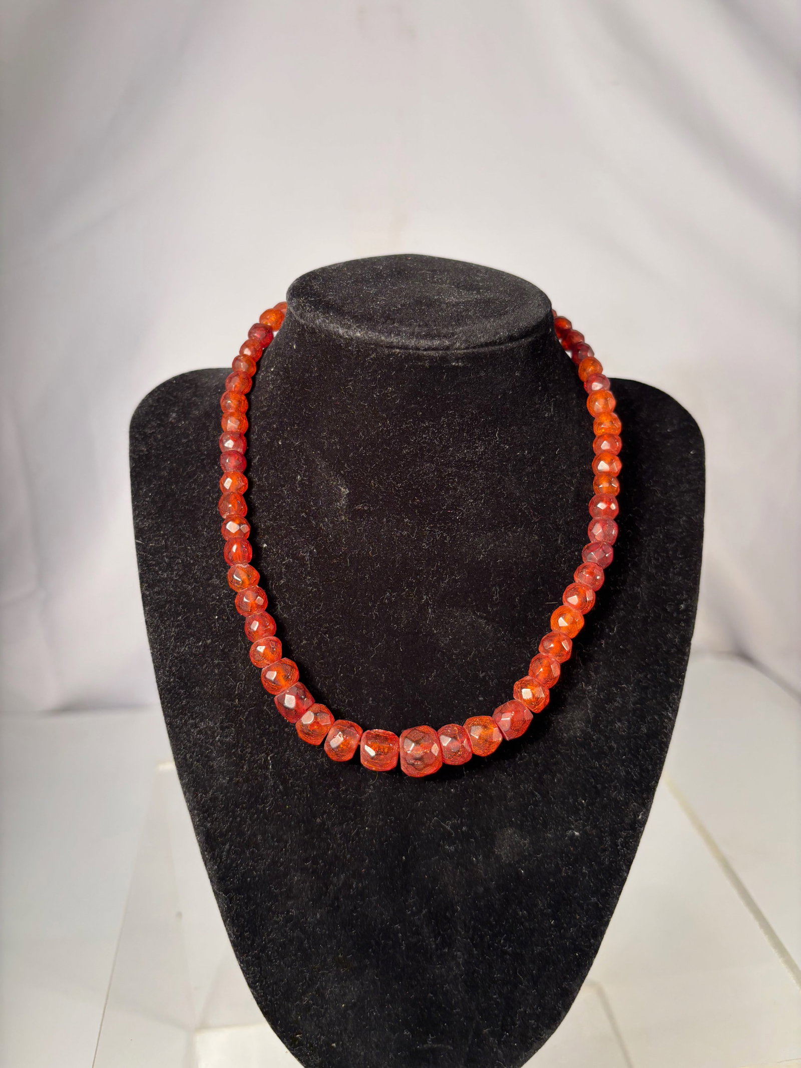A Faceted Amber Bead Necklace: This necklace is composed of faceted translucent amberbeads, displaying warm honey to reddish-brown tones with attractive internal variation. The faceted surfaces catch and reflect light, giving the s