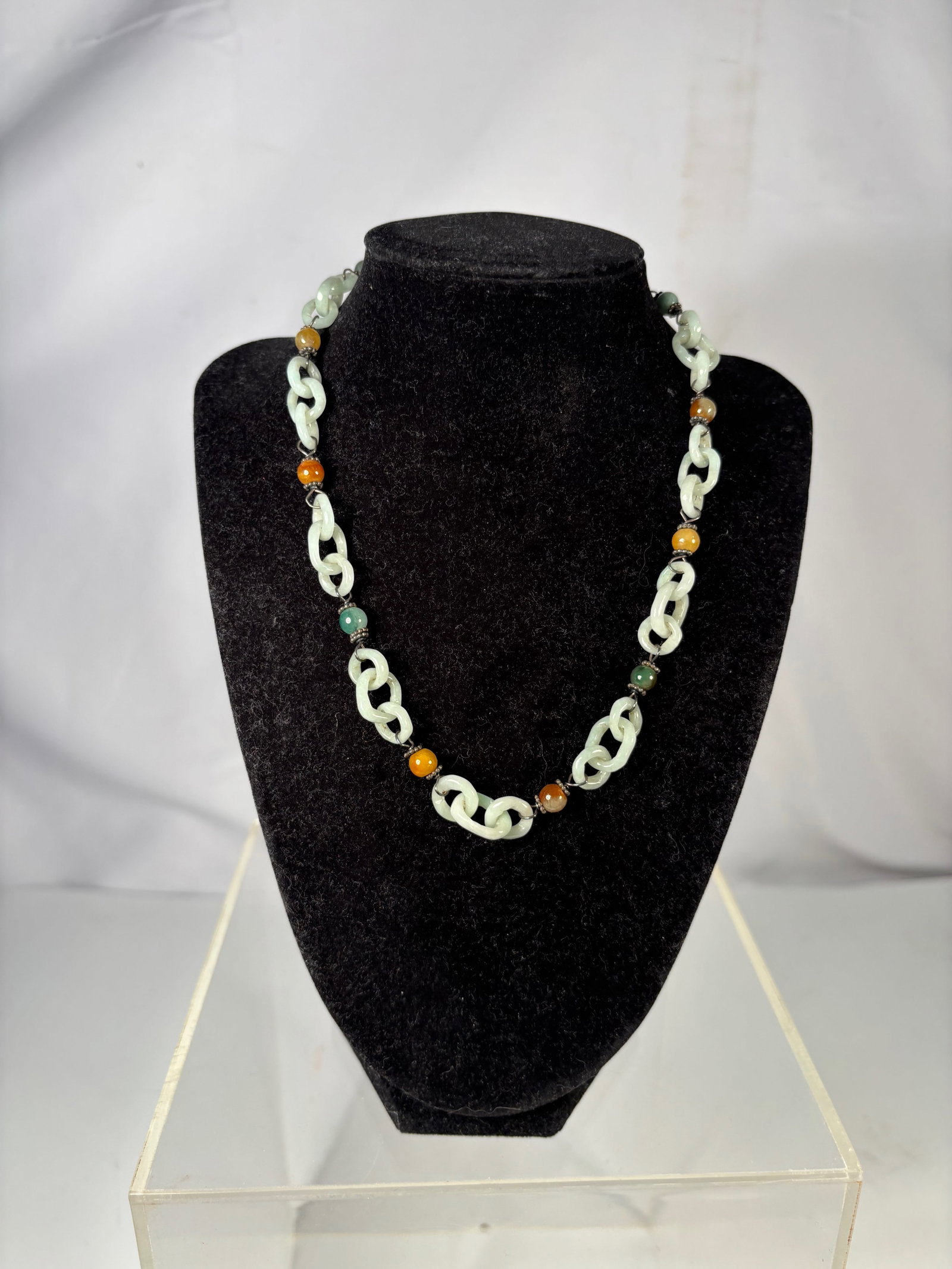 A Chinese Jadeite Link Necklace with Hardstone Beads: Chinese necklace composed of carved jade link elements interspersed with assorted hardstone beads of various colors. The carved links are fashioned in an interlocking chain form, creating a continuous