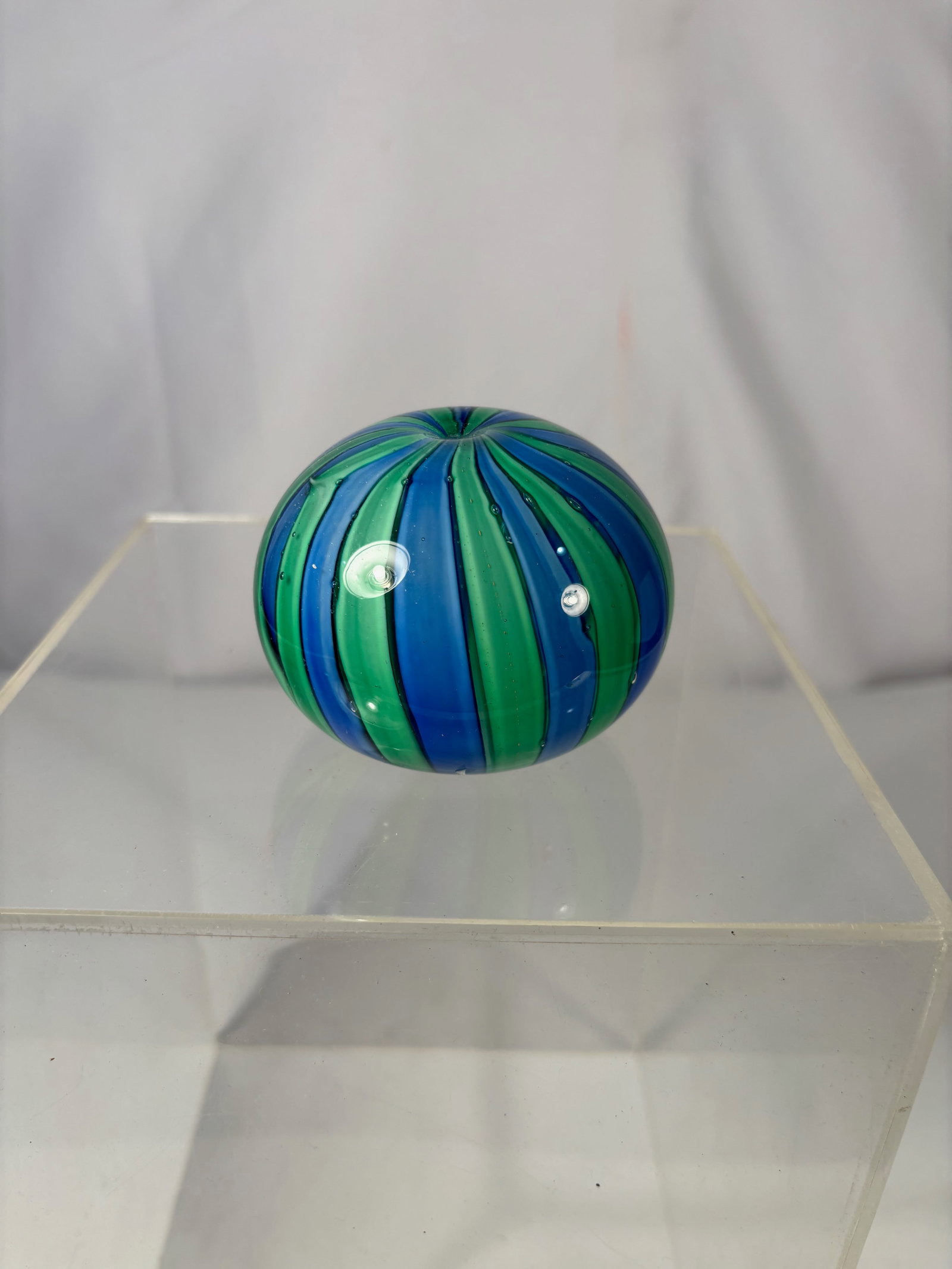 Italian Murano Style Art Glass Paperweight, Blue Green Striped Design: This decorative art glass paperweight features a rounded, domed form with alternating blue and green vertical stripes created through layered cane work. The vivid color contrast and smooth, polished s