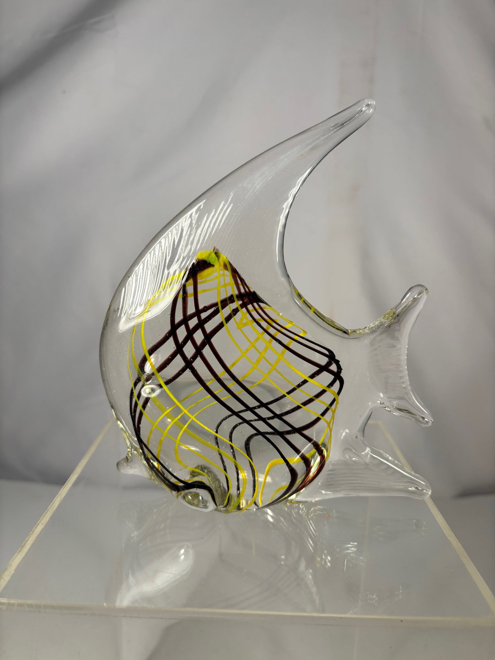 Murano Style Art Glass Fish Sculpture, Clear Glass w/ Yellow & Black Decoration: This decorative art glass sculpture is formed in the shape of a stylized fish, featuring a clear glass body with elegantly extended fins and tail. The interior is accented with flowing yellow and blac