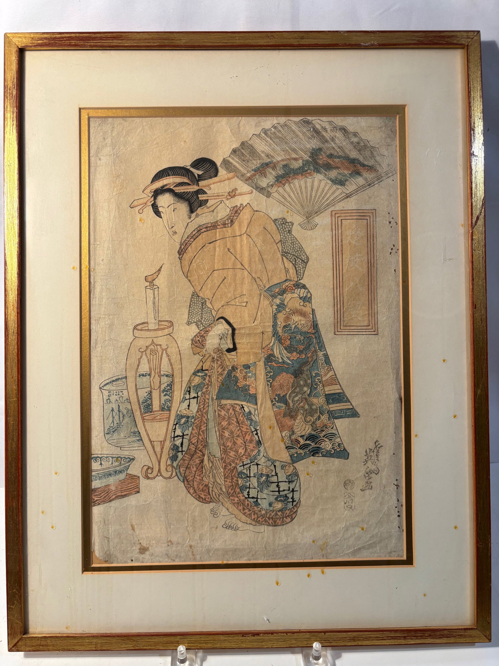 Keisai Eisen (1790–1848), Japanese Bijin-ga Woodblock Print, Beauty in an Interior, Edo Period: A finely detailed Japanese ukiyo-e woodblock print by Keisai Eisen (1790–1848), depicting an elegant standing beauty in an interior setting beside a tall oil lamp stand and ceramic vessels. The figu