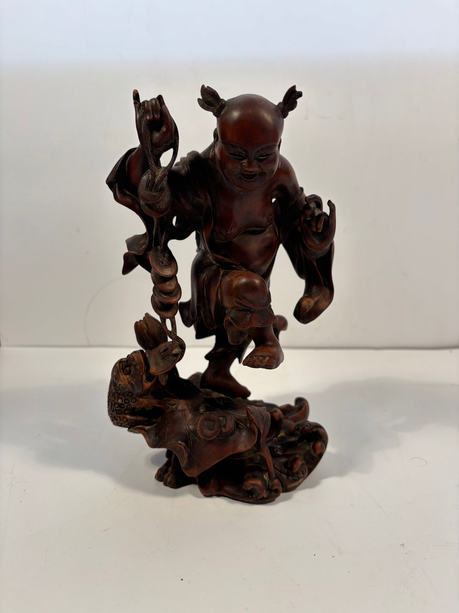 A Chinese hand carvd Child with a Three leg toad boxwood statue: Qing Dynasty (1644-1912), The joyful expression and hairstyle suggest the figure is a child deity or immortal.Dimensions? Height: 9.5 inches.