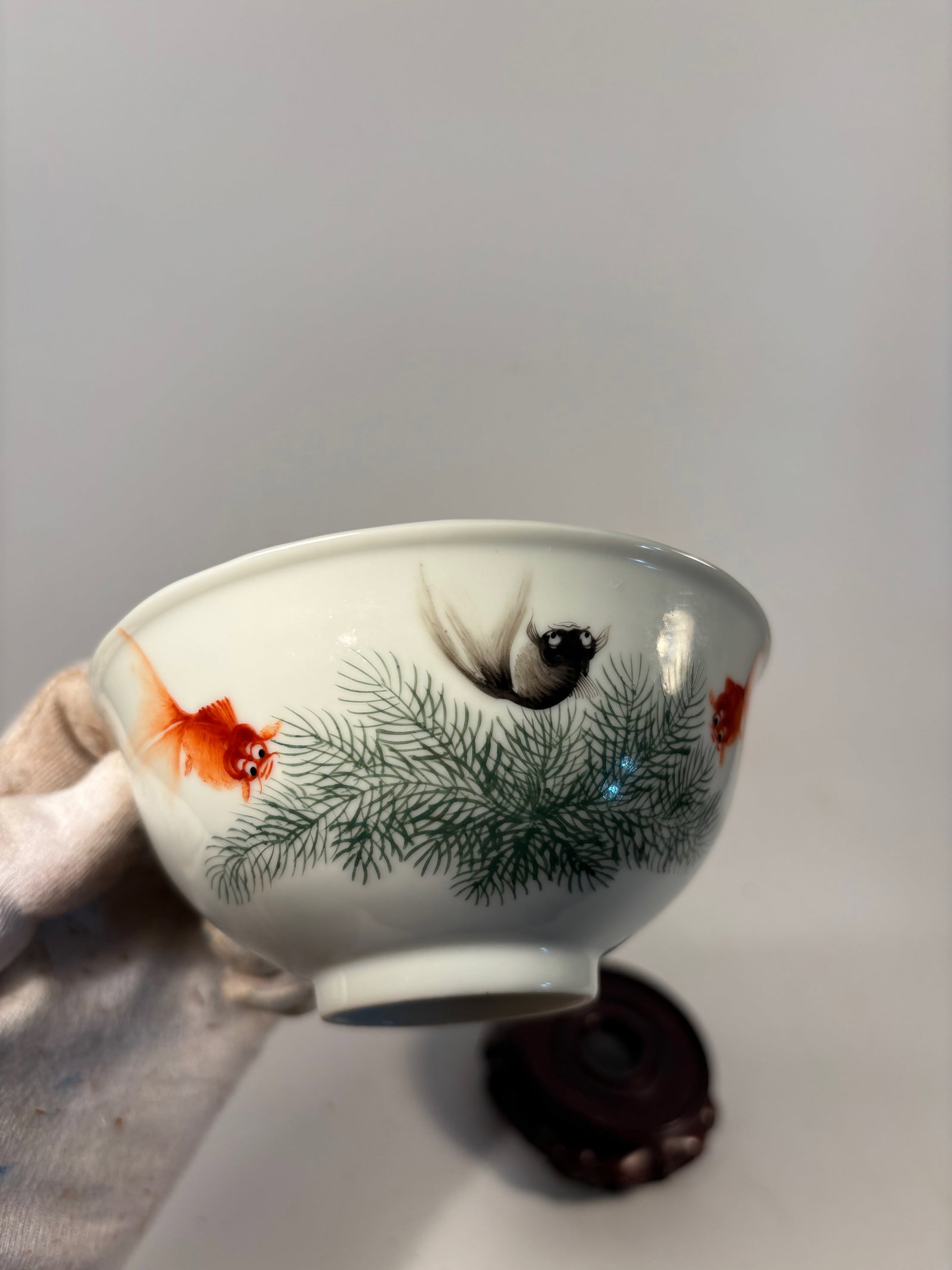 A Chinese Porcelain Bowl with Goldfish and Pine Decoration: Republic period (1912-1949) ; Delicately potted with a rounded body and slightly flared rim, this porcelain bowl is finely painted in famille verte and iron-red enamels with a pair of goldfish swimmin