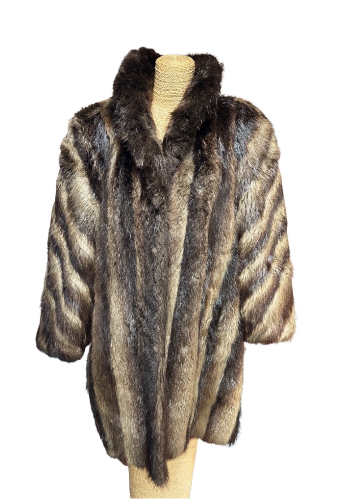 Natural Fur Coat with Darker Collar Trim, Garber Furs Chicago: A full-length coat made of natural, unshorn raccoon fur, featuring rich color gradations from silver-gray to deep brown. The pelts are arranged vertically to emphasize the natural striping and fullnes