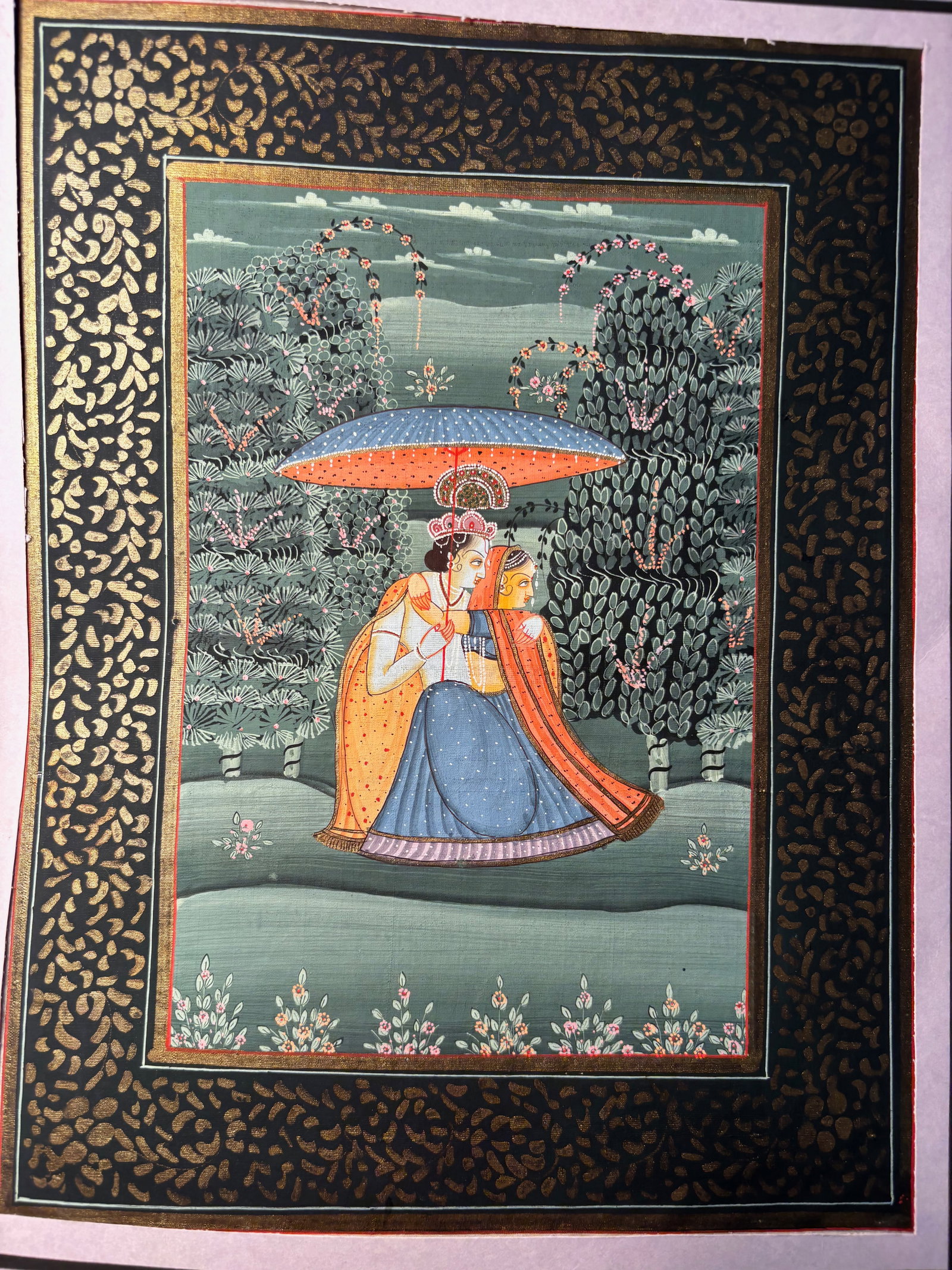 Indian Gouache Miniature of a Royal Couple Beneath a Parasol: 19th century; A finely detailed Indian miniature painting, likely Rajasthan or Mughal school, depicting a royal couple in an intimate embrace beneath a blue and orange parasol. The figures are seated 