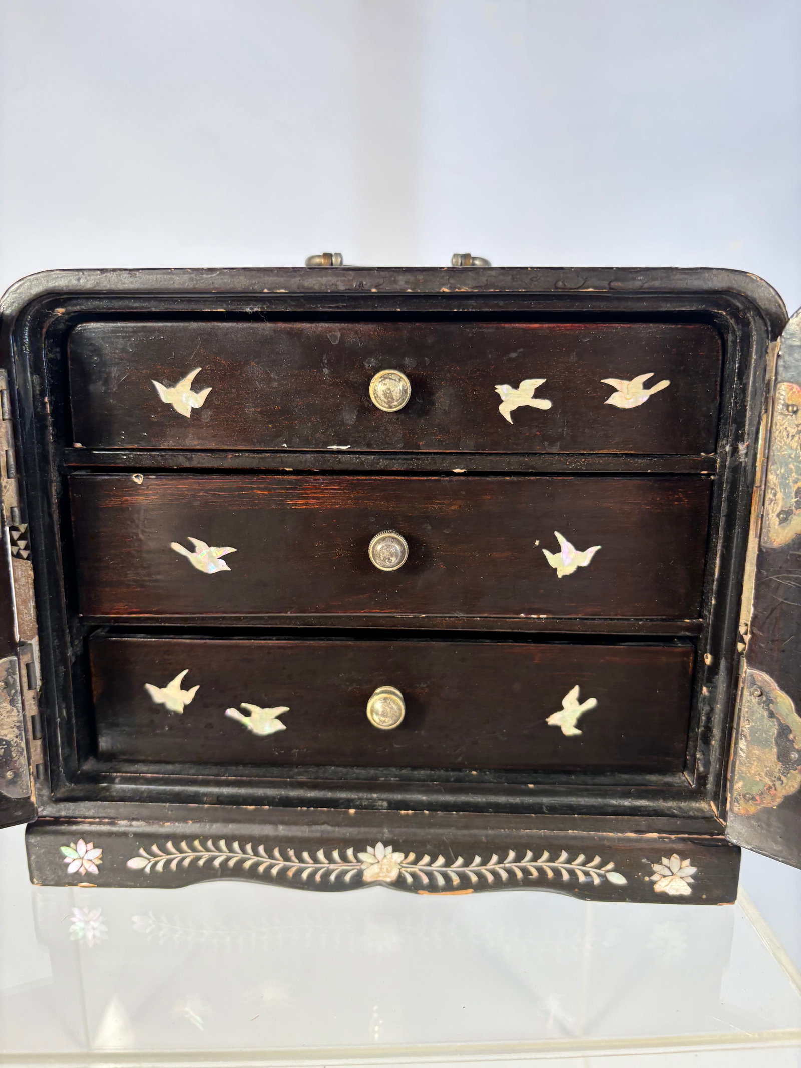An Asian Black Lacquer and Mother-of-Pearl Inlaid Jewelry Cabinet: 19th century, An asian black lacquer jewelry cabinet with mother-of-pearl inlay, late Qing/Republic period, the rectangular form with hinged double doors opening to reveal multiple drawers, decorated 