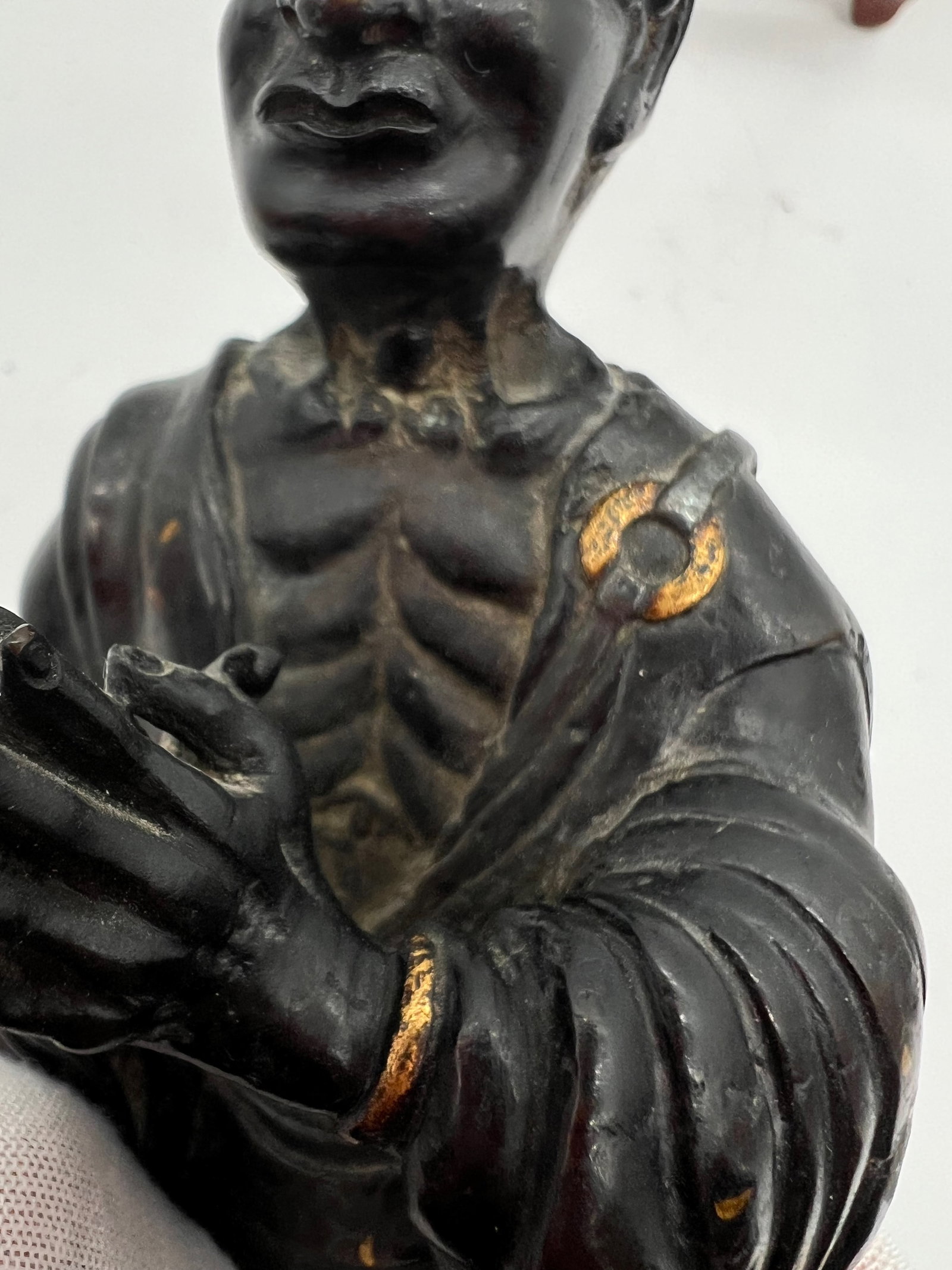 A Japanese silver inlaid gilt bronze monk statue with marble vase: 19th century ; The statue depicted in the images appears to be a bronze or brass figure of a Buddhist monk or an enlightened being (arhat or luohan). The statue has silver inlaid and gilt on the bronz