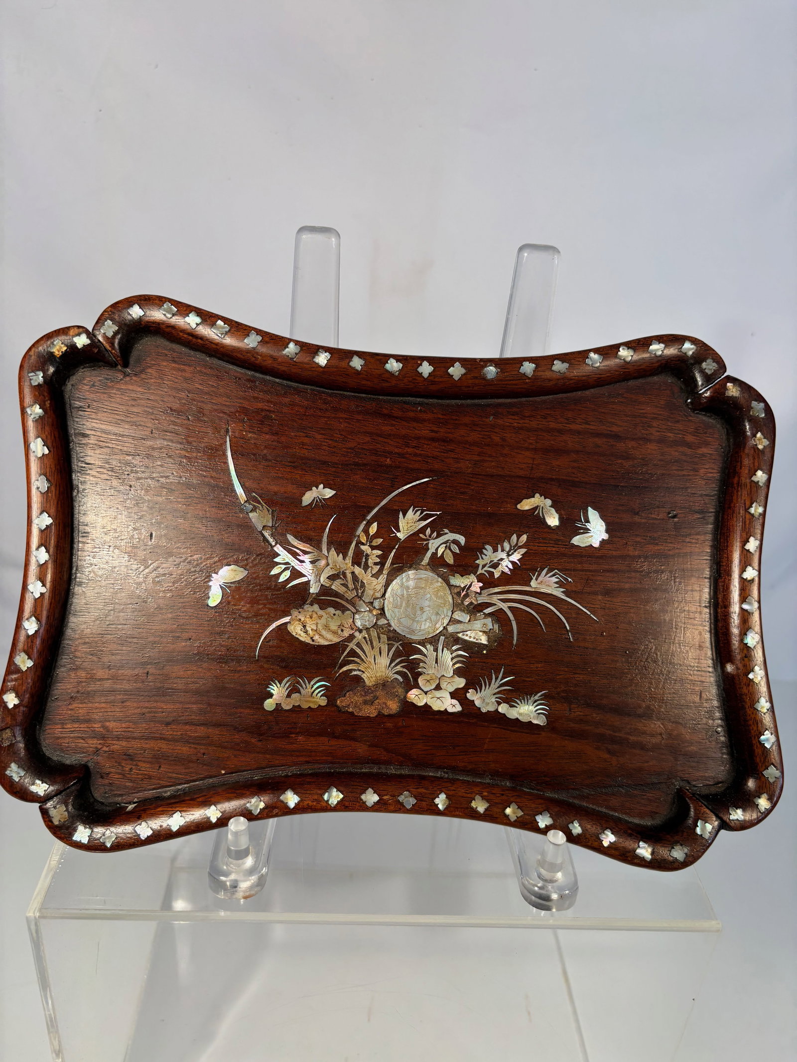 A Chinese rosewood and Mother-of-Pearl Inlaid Tray: Qing Dynasty(1644-1912);Of rectangular form with shaped corners and raised rim, the hardwood tray finely inlaid in mother-of-pearl with a central still-life of flowers, leaves, and scholar’s objects