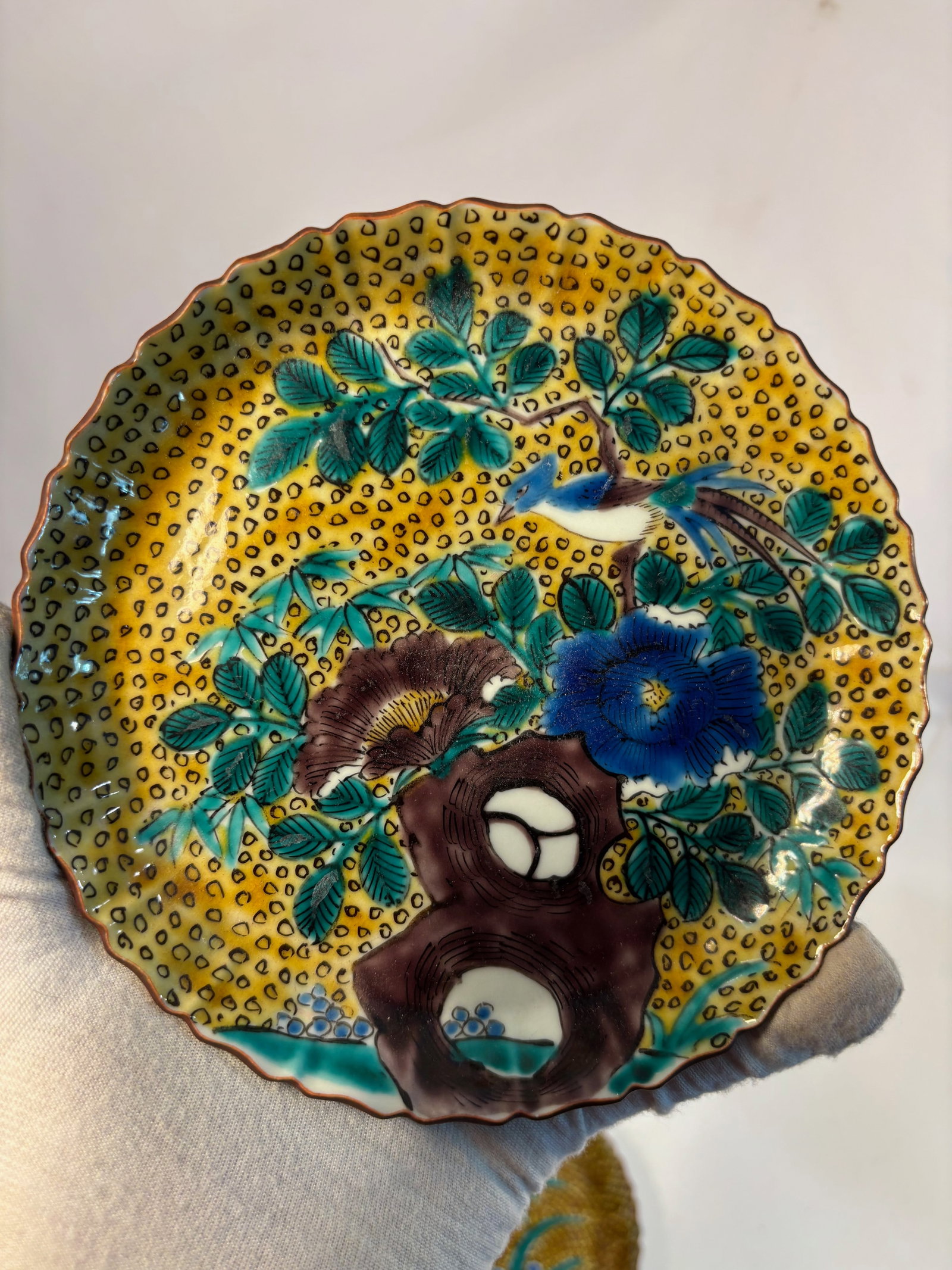 A Japanese Kokutani Lobed Dish, Meiji Period (1868–1912): Lobed and delicately molded, decorated in the Kokutani palette of green, yellow, aubergine, blue and white glazes, the interior with floral and bird motifs against a dotted yellow ground, the reverse 