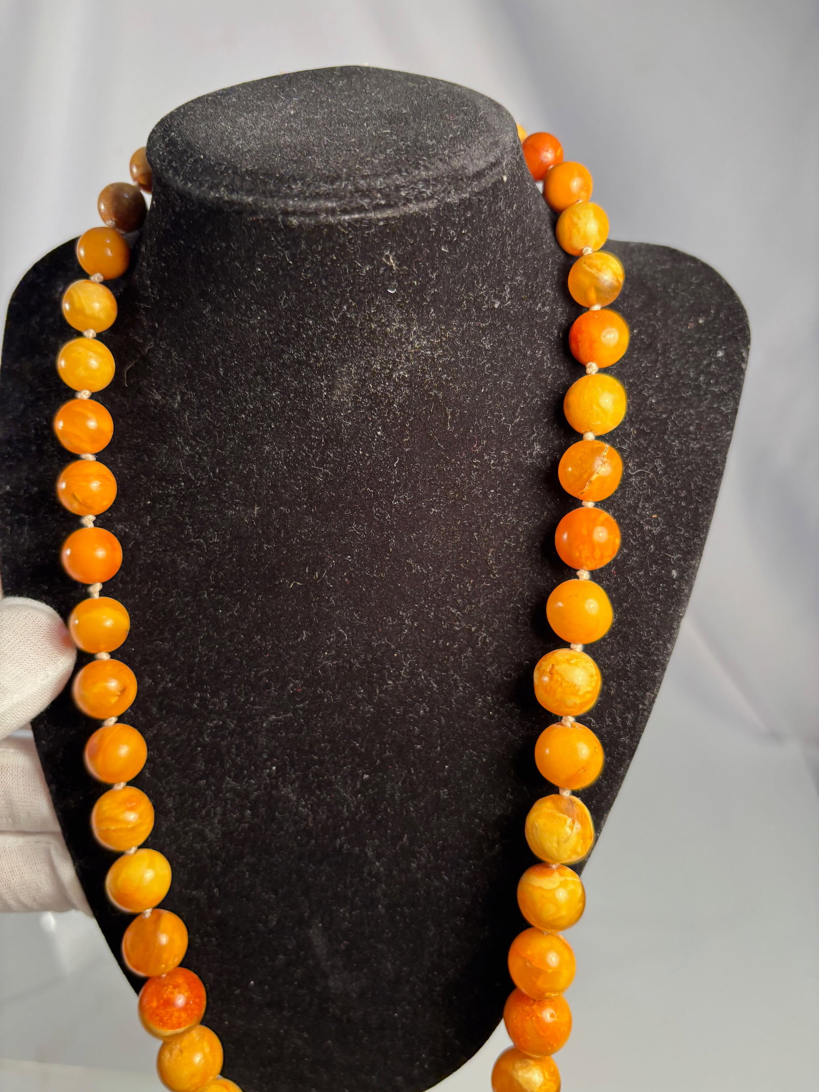 A Fine Butterscotch Baltic Amber Graduated Bead Necklace, 63.42 g: Composed of graduated butterscotch Baltic amber beads, ranging from pale yellow to rich orange in tone, with characteristic marbling and natural inclusions. Smoothly polished and strung on cord. Dimen