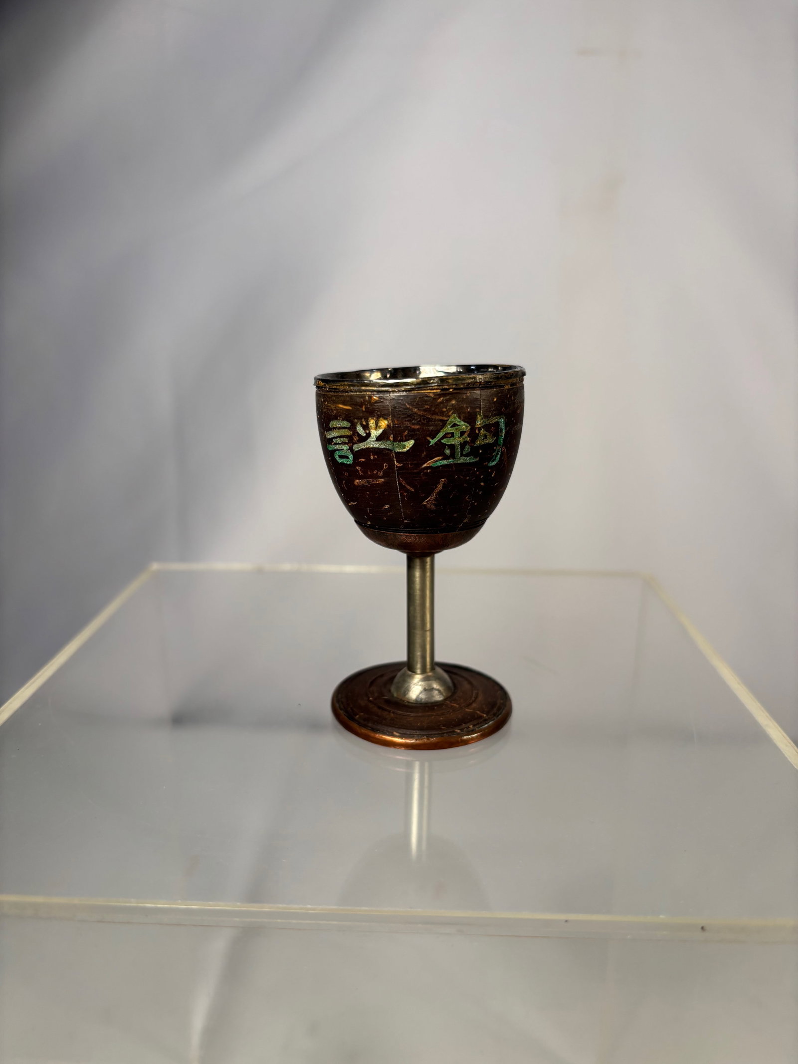 Chinese Silver-Mounted Coconut Shell Goblet with Silver-Lined Interior: Chinese coconut shell goblet with a silver-lined interior and silver-mounted rim, raised on a non-silver metal stem and foot. The exterior of the coconut shell is carved and decorated with engraved