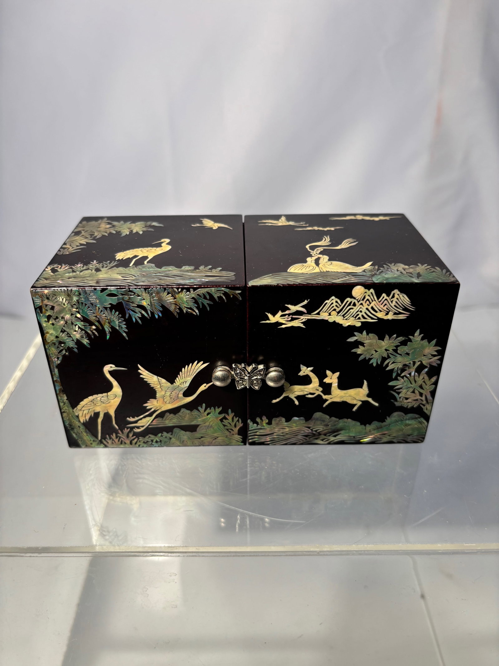 A Japanese Meiji Period Black Lacquer and Mother-of-Pearl Inlaid Box with Cranes and Deer: Rectangular Japanese lacquer box, Meiji period, decorated in mother-of-pearl inlay depicting cranes, deer, birds, pine trees, and landscape motifs. The hinged double doors open to a fitted interior wi