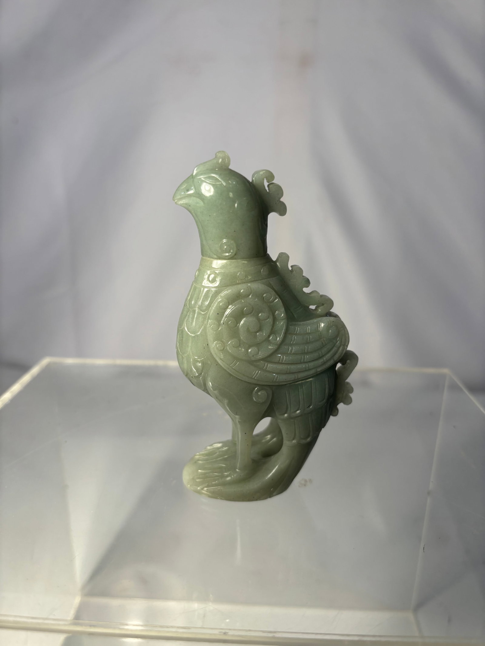 A Chinese Carved Jade Bird Figure vase with cover: A Chinese Carved Jade Bird Figure vase with cover in the form of a stylized bird, decorated with archaistic scroll and feather motifs. The Jade is of a celadon-green tone with natural inclusions.The b