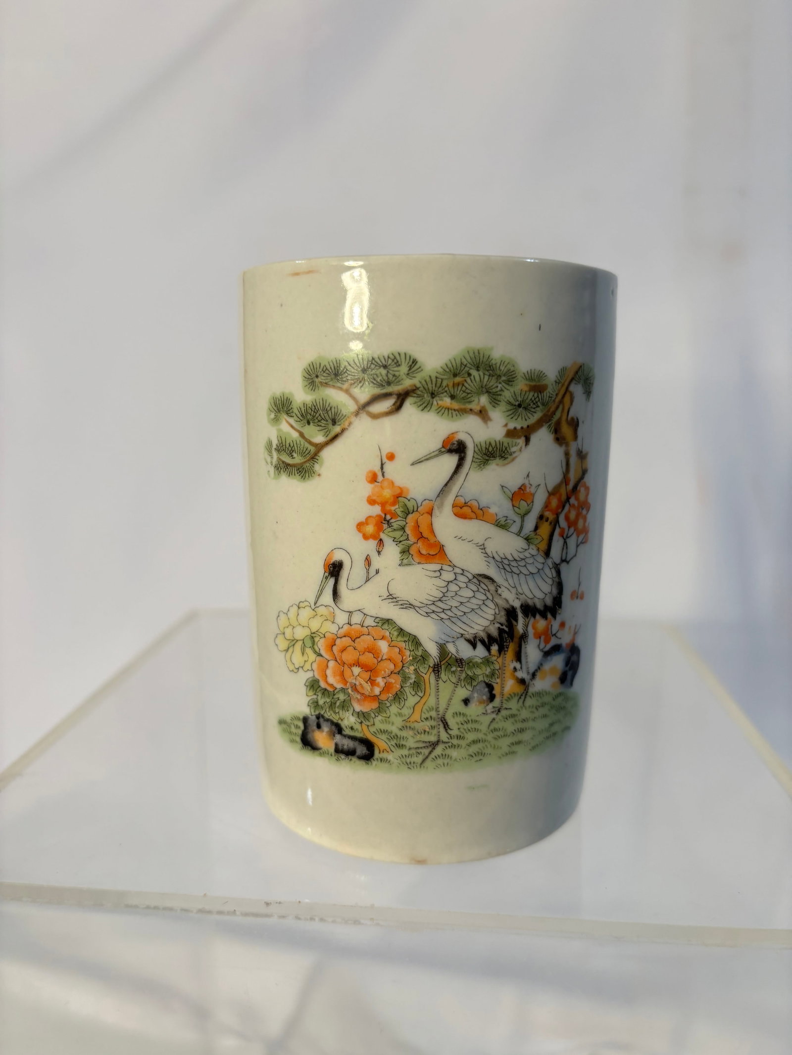 A Chinese Famille Rose Porcelain Brush Pot: Qing Dynasty(1644-1912); A Chinese porcelain brush pot (bitong) of cylindrical form, finely decorated in famille rose enamels with cranes among pine branches and flowering plants, symbolizing longevit