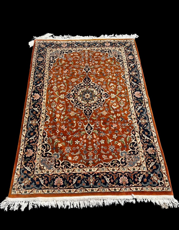 Persian Hand-Knotted Tabriz Design Wool Rug, Floral Medallion Approx. 77 x 48 in.: Persian rug featuring a classic central medallion design with intricate scrolling floral motifs throughout. The field is rendered in a rich rust/ red tone, framed by a contrasting navy blue border wit