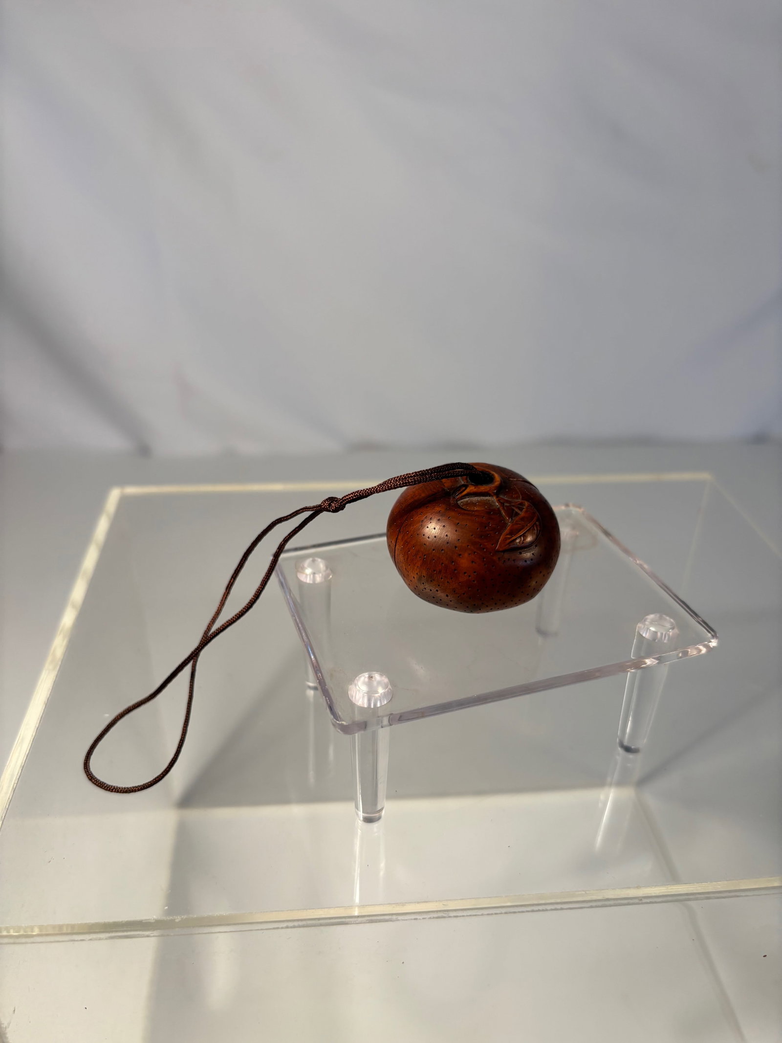 A Japanese Carved boxwood Netsuke of a Chestnut with Interior Figure: Meiji period(1868-1912) ,A Japanese carved wood netsuke, fashioned as a chestnut with naturalistic veining, the form opening to reveal a finely carved interior figure. Smooth, warm patina with himotos
