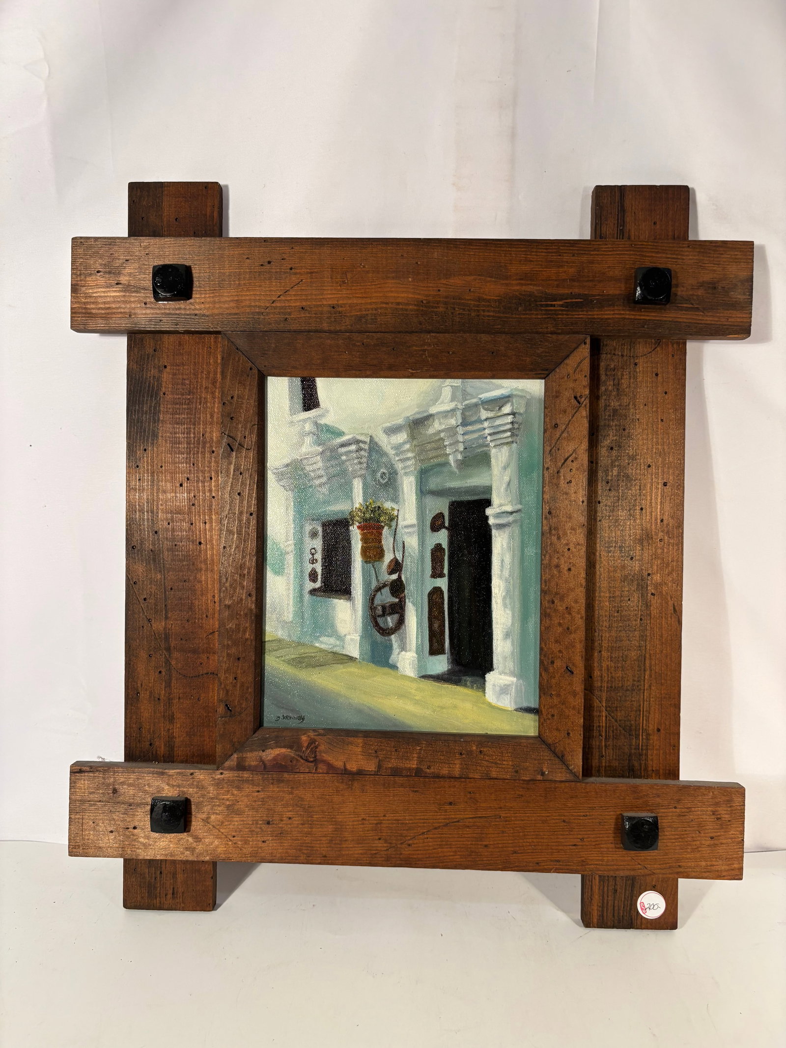 Dolores Kenney “Spanish Shop?? Oil on Canvas in Rustic Southwestern Frame: A charming architectural study depicting a Spanish colonial storefront façade with white stucco columns, carved lintels, hanging planter, and old metal hardware. The artist uses soft blue-green