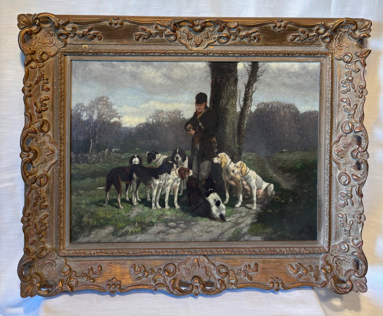 Large European Oil Painting, Hunter with Hounds, 19th Century Sporting Scene, 30 x 24 in, Gilt: Oil on canvas depicting a hunter standing beneath a tree surrounded by a pack of hounds in a wooded landscape. The composition captures a classic European sporting scene, with multiple dogs rendered i