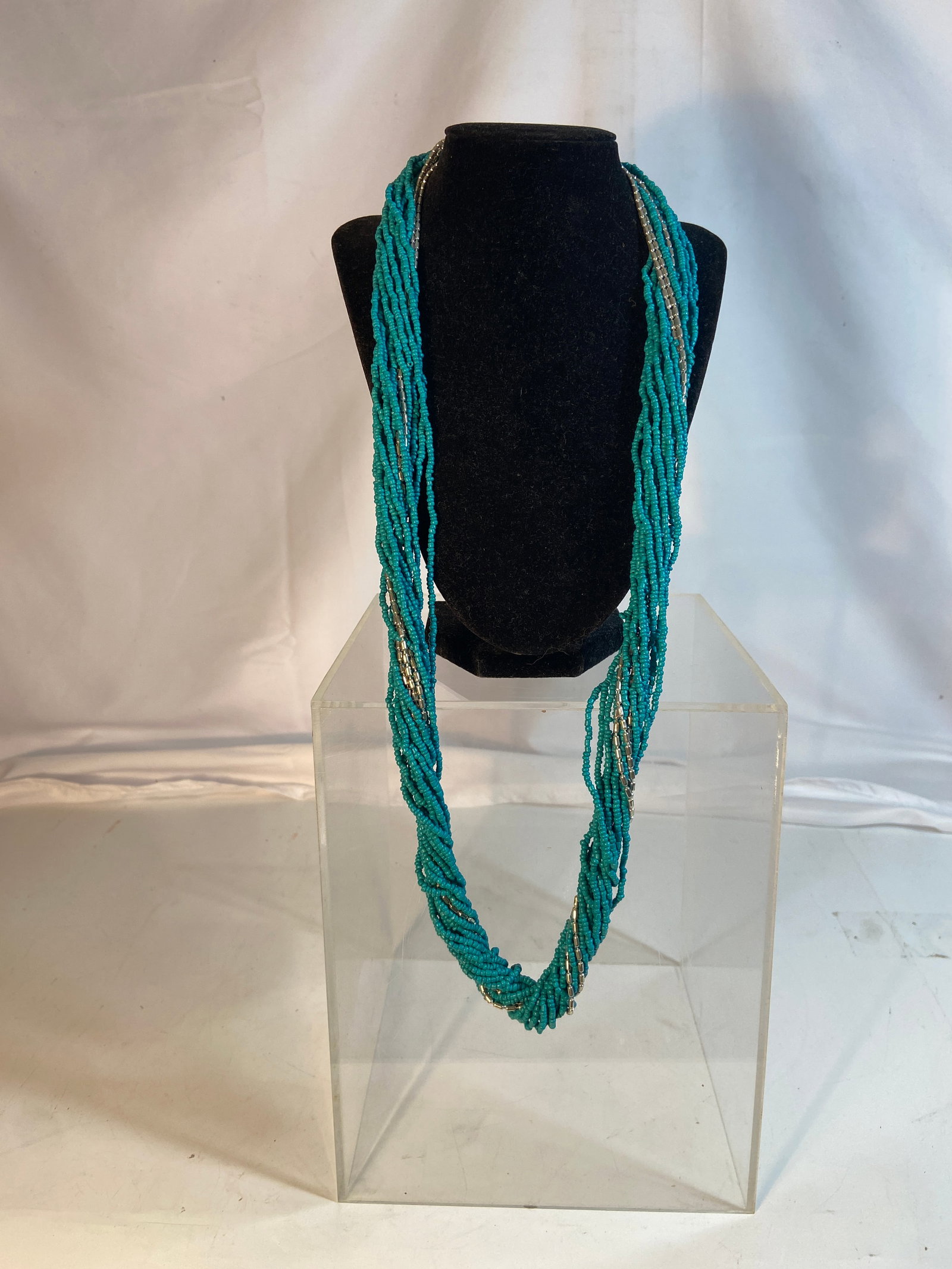 Multi Strand Turquoise Color Seed Bead Necklace: Vintage multi-strand turquoise color seed bead necklace with silver-tone accent beads and clasp. Designed in a layered torsade style with numerous strands creating a dramatic draped appearance. Length