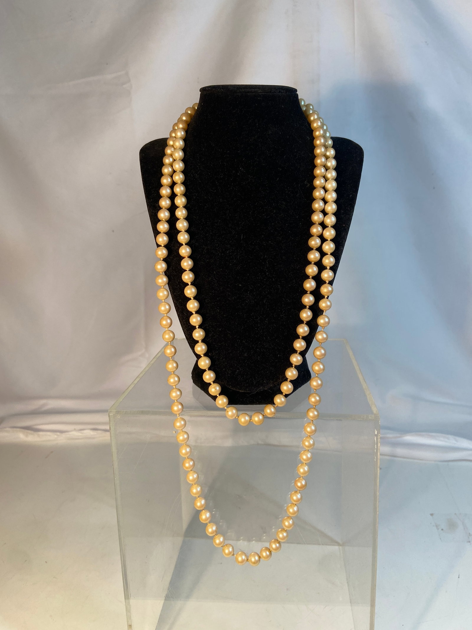 Vintage long Strand Faux Pearl Opera Necklace, 56 Inches: Vintage long strand opera-length necklace composed of cream colored faux pearls with hand-knotted construction and decorative clasp. Measuring approximately 56 inches long, the necklace may be worn as