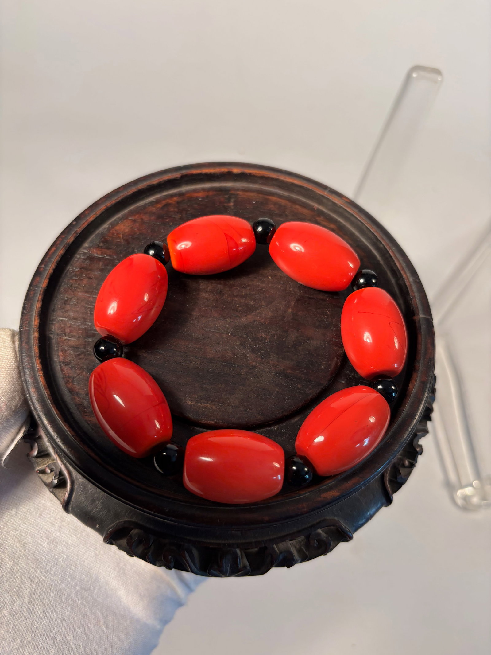 A Vintage Red Glass Bead Bracelet with Black Spacers: A striking vintage bracelet composed of large oval red glass beads with subtle swirled marbling, separated by small black round glass spacers. The bracelet is strung on elastic cord for adjustable