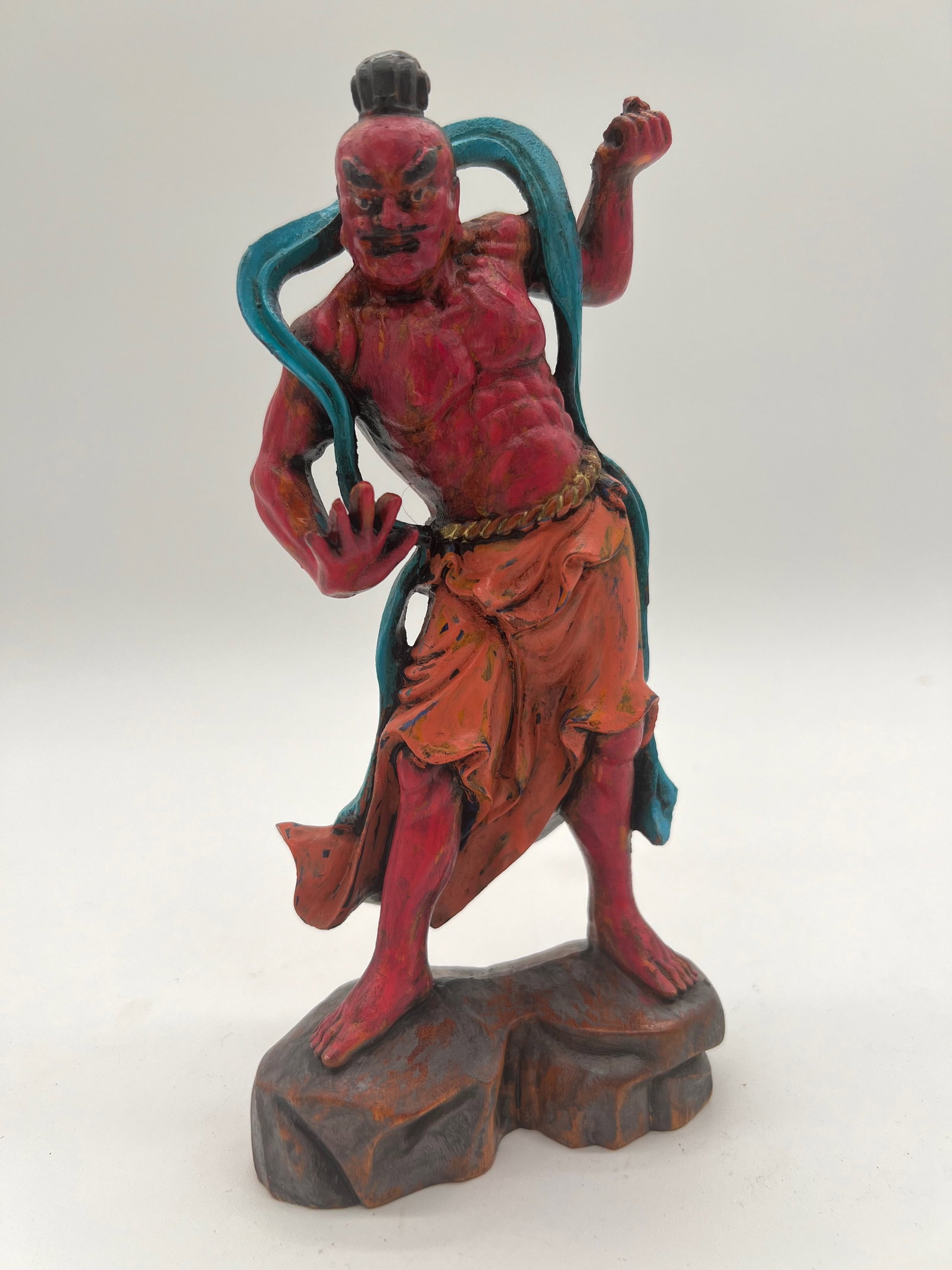 A Chinese hand carved boxwood Nio guardian figurine: Early 20th , The vibrant red and blue colors, along with the muscular form and dramatic pose, suggest it might be a representation of a guardian figure or deity. Dimensions?Height: 8 inches