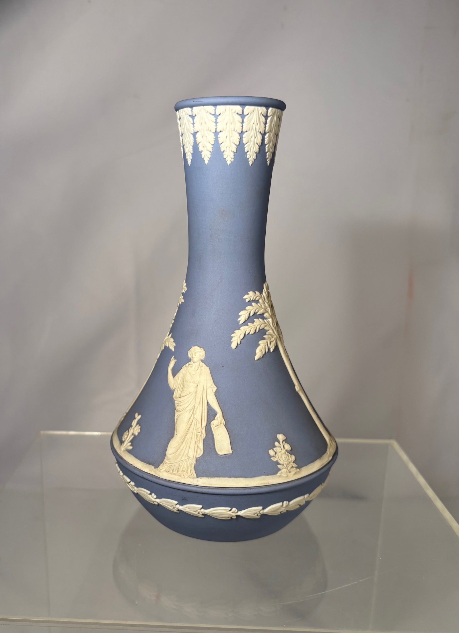 A Wedgwood Blue Jasperware Classical Relief Vase, England 1972: Blue Wedgwood Jasperware vase featuring classical white relief decoration depicting figures and trees. Marked WEDGWOOD MADE IN ENGLAND 72 to the base indicating production year 1972. Height: 8 inches.