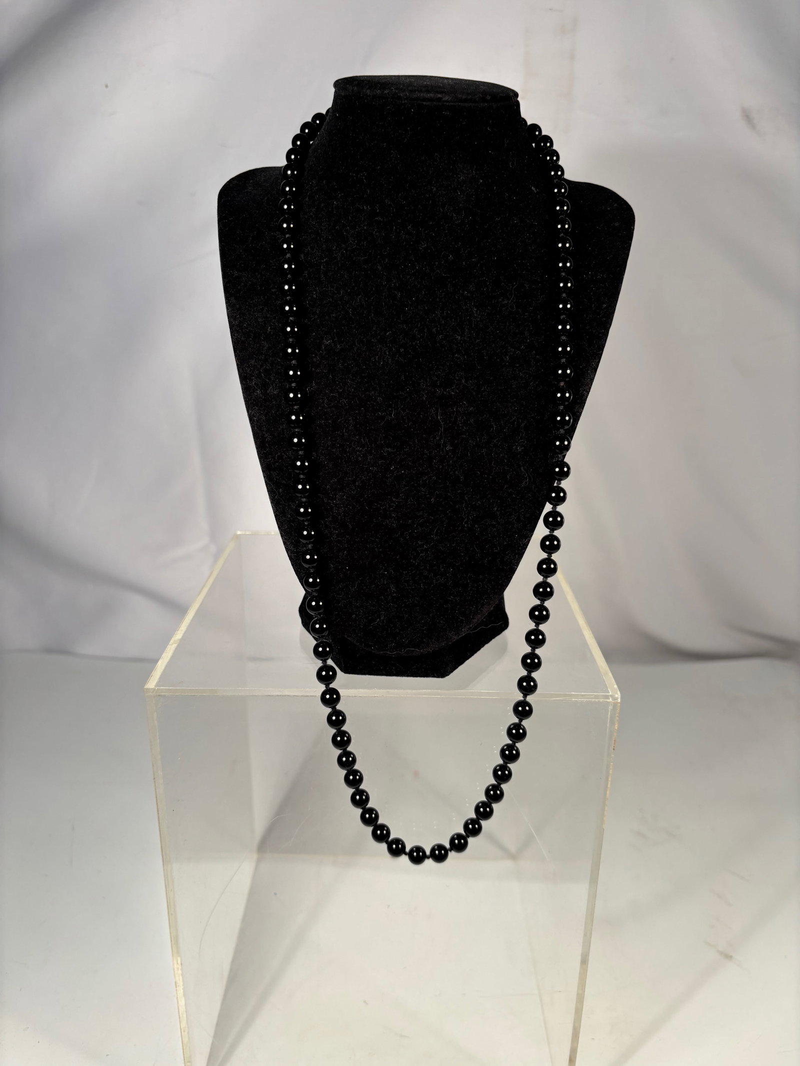 An Opera Length Black Onyx Bead Necklace: Long strand necklace composed of polished round black onyx beads with a glossy finish. The beads are uniformly shaped and strung in a continuous strand, forming an elegant classic design. Necklace Len