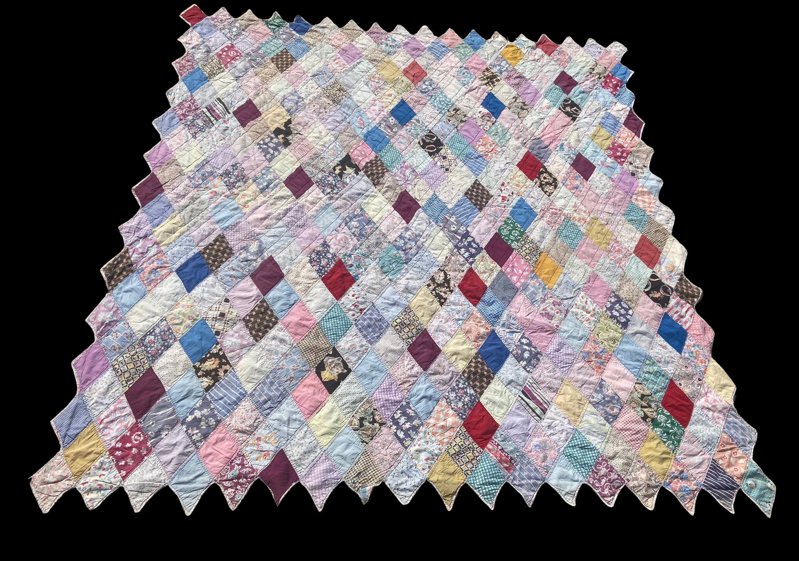 Vintage Handmade Patchwork Quilt, Diagonal Strip Scrap Cotton w/ Scalloped Edge: This vintage handmade patchwork quilt features a diagonal strip design composed of assorted scrap cotton fabrics, including floral, geometric, and novelty prints. The composition is arranged in a live