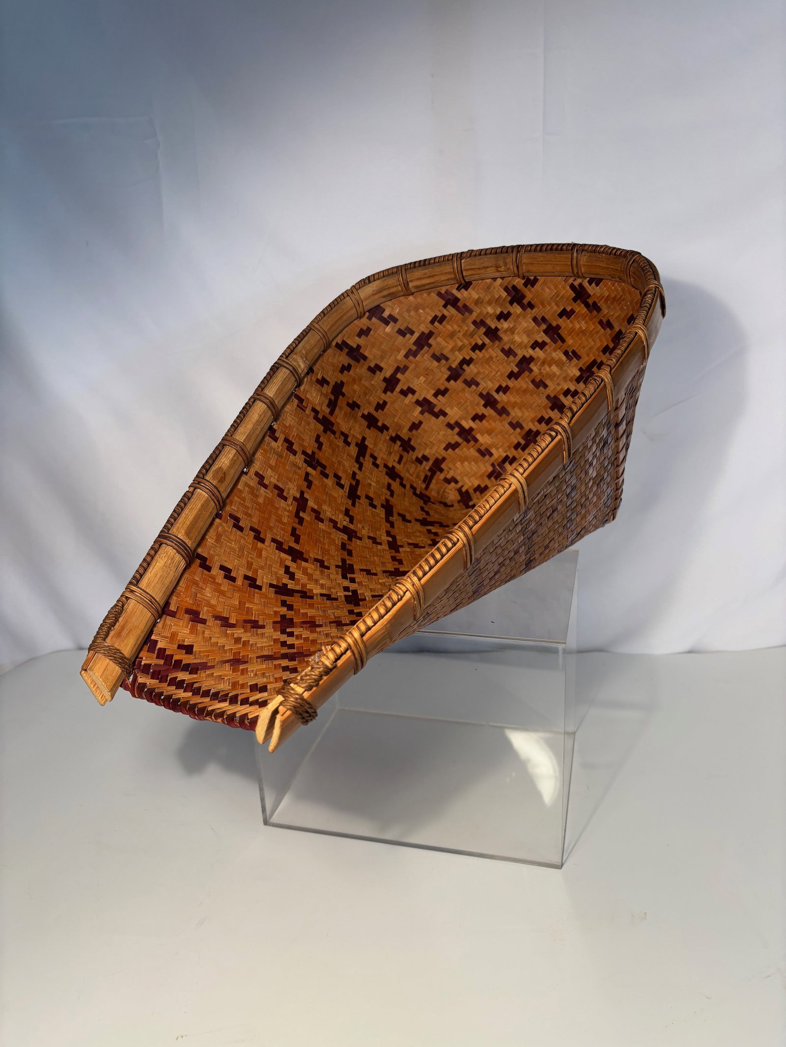 Vintage Handwoven Bamboo Storage Basket: A finely handwoven bamboo basket, of tapering form with slightly flared rim, decorated with a geometric diamond pattern in contrasting dark and reddish-brown weaving. The rim is reinforced with split 