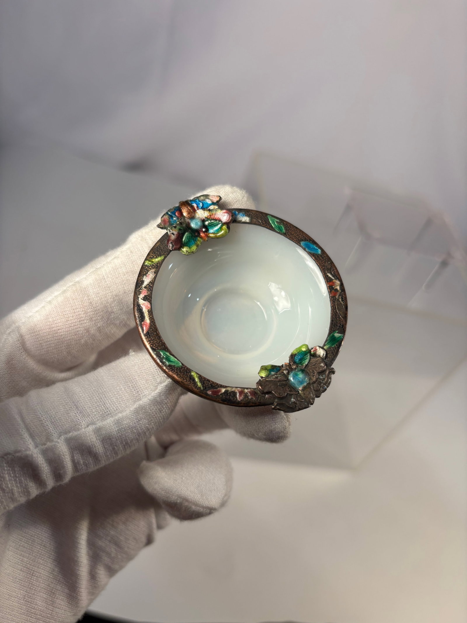 A Chinese Enamel Glass Dish: Qing dynasty(1644-1912); A small oval enameled glass dish, the shallow white glass basin set within a metal-mounted rim, the rim decorated with polychrome enamel floral motifs in turquoise, green,