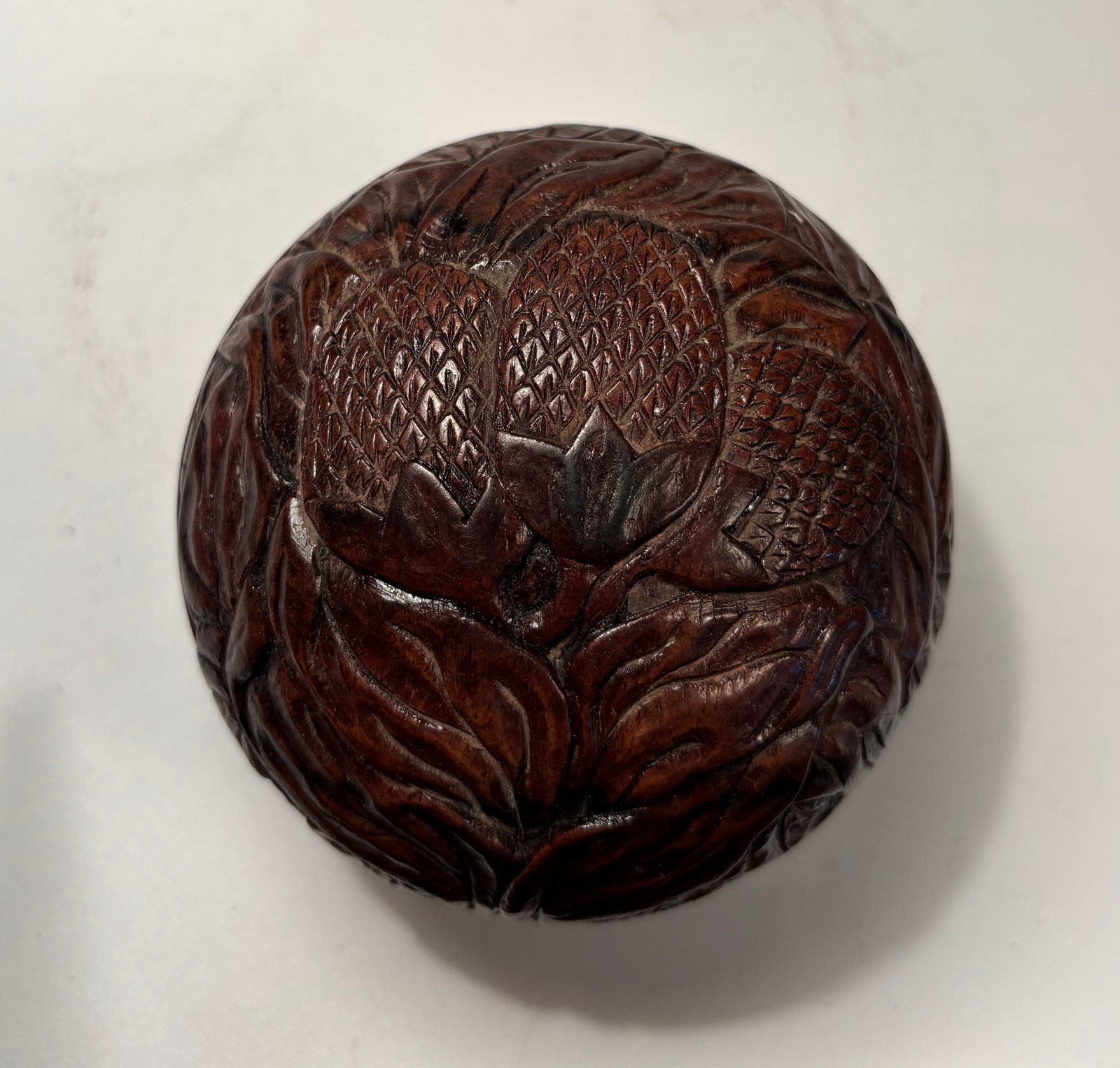 A Chinese hand carved huanghuali box: QING DYNASTY(1644-1912); A finely carved Chinese box made from huanghuali wood, shaped in the form of a naturalistic fruit or seed pod, with high-relief carving of overlapping leaves and scaled surfac