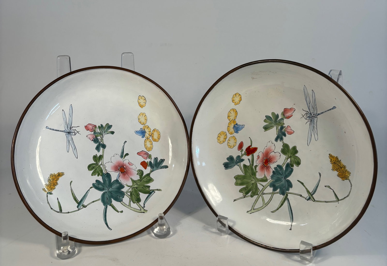 Pair of Chinese Hand-Painted Enamel Dishes with Floral and Dragonfly Design with mark: Qing Dynasty (1644-1912); A pair of finely crafted Chinese enamel dishes, delicately hand-painted with flowering branches, dragonflies, and butterflies. The vibrant design features pink blossoms,