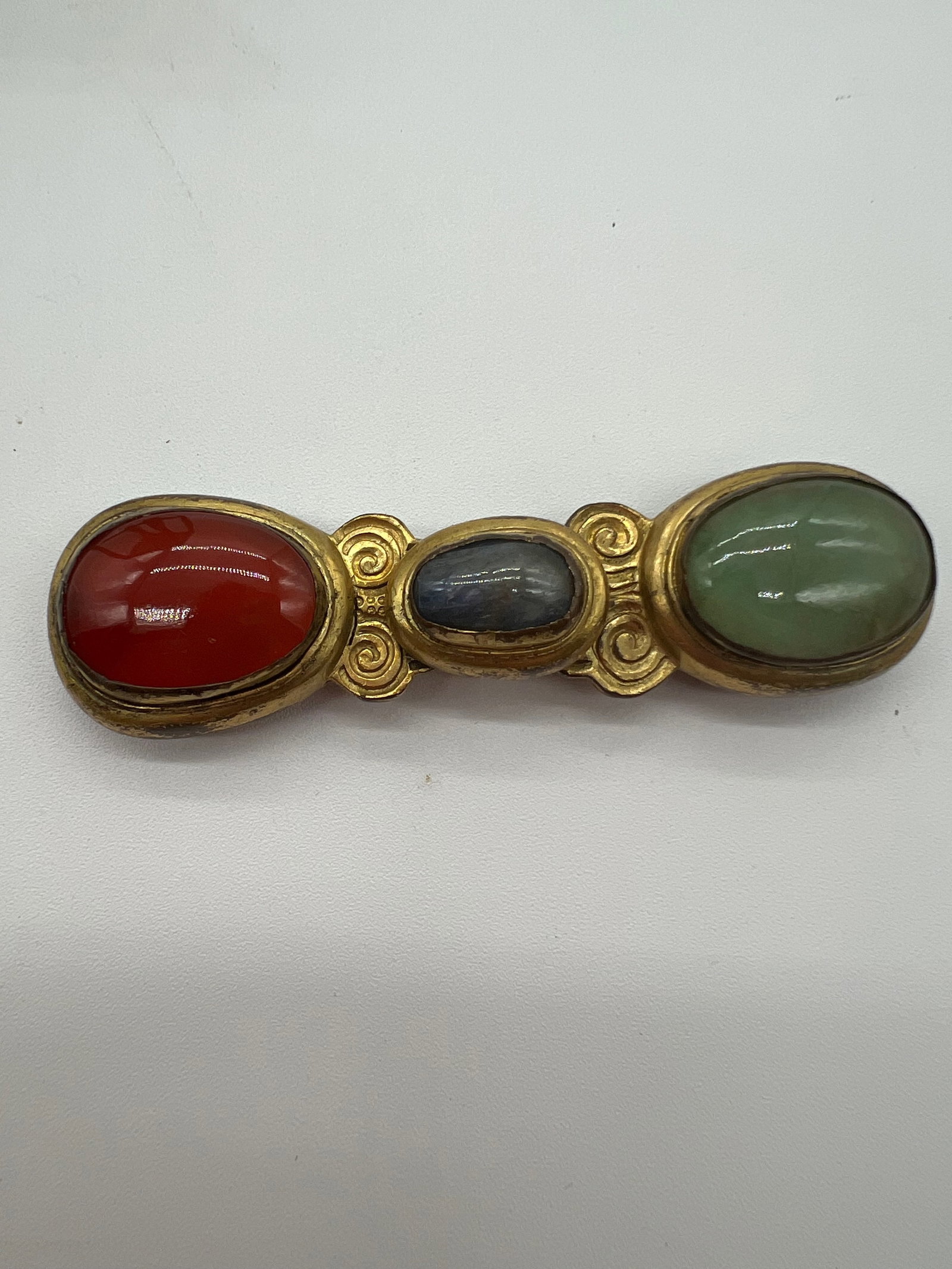 A Chinese Gilt Bronze Jeweled Belt Buckle: Qing Dynasty (1644-1912); The buckle featuring three oval stones set in what appears to be a gilded metal frame. The stones look like they might be semi-precious stone like jade , carnelian and