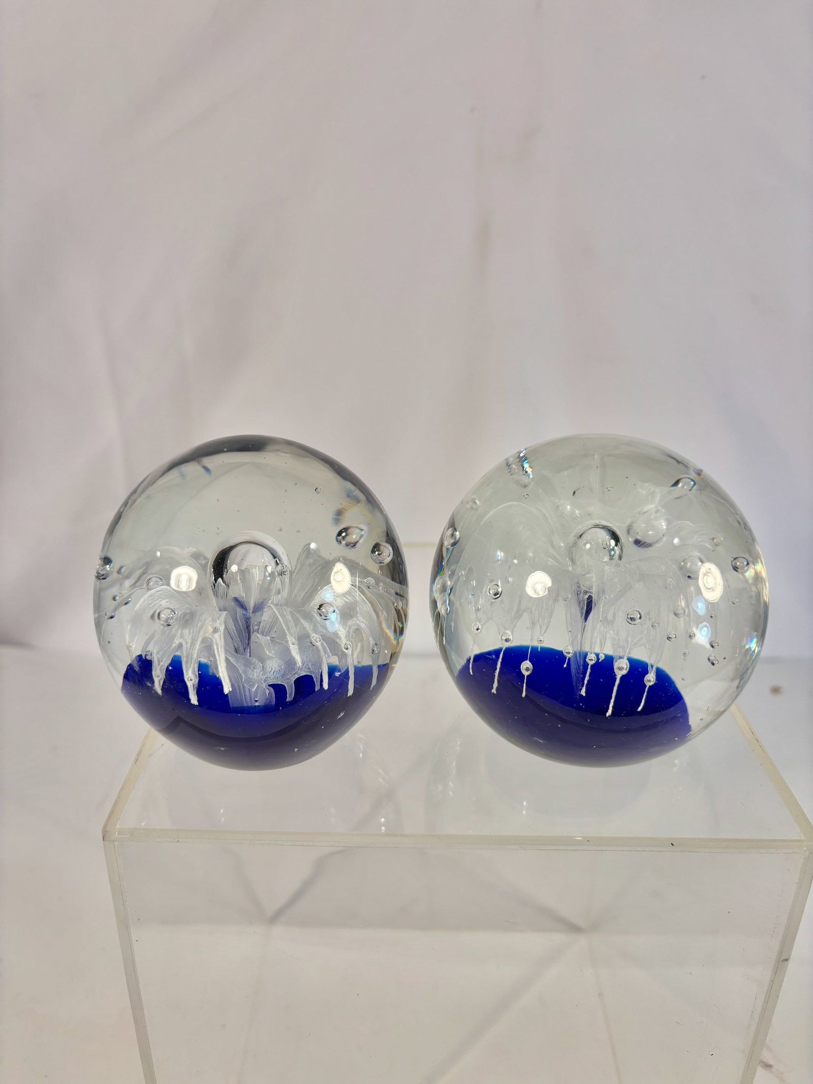 Set of 2 Art Glass Jellyfish Paperweights, Blue & Clear: 2 contemporary studio art glass paperweights, each featuring an internal jellyfish design with trailing tentacle-like white inclusions and suspended air bubbles. The lower half contains a deep cobalt-