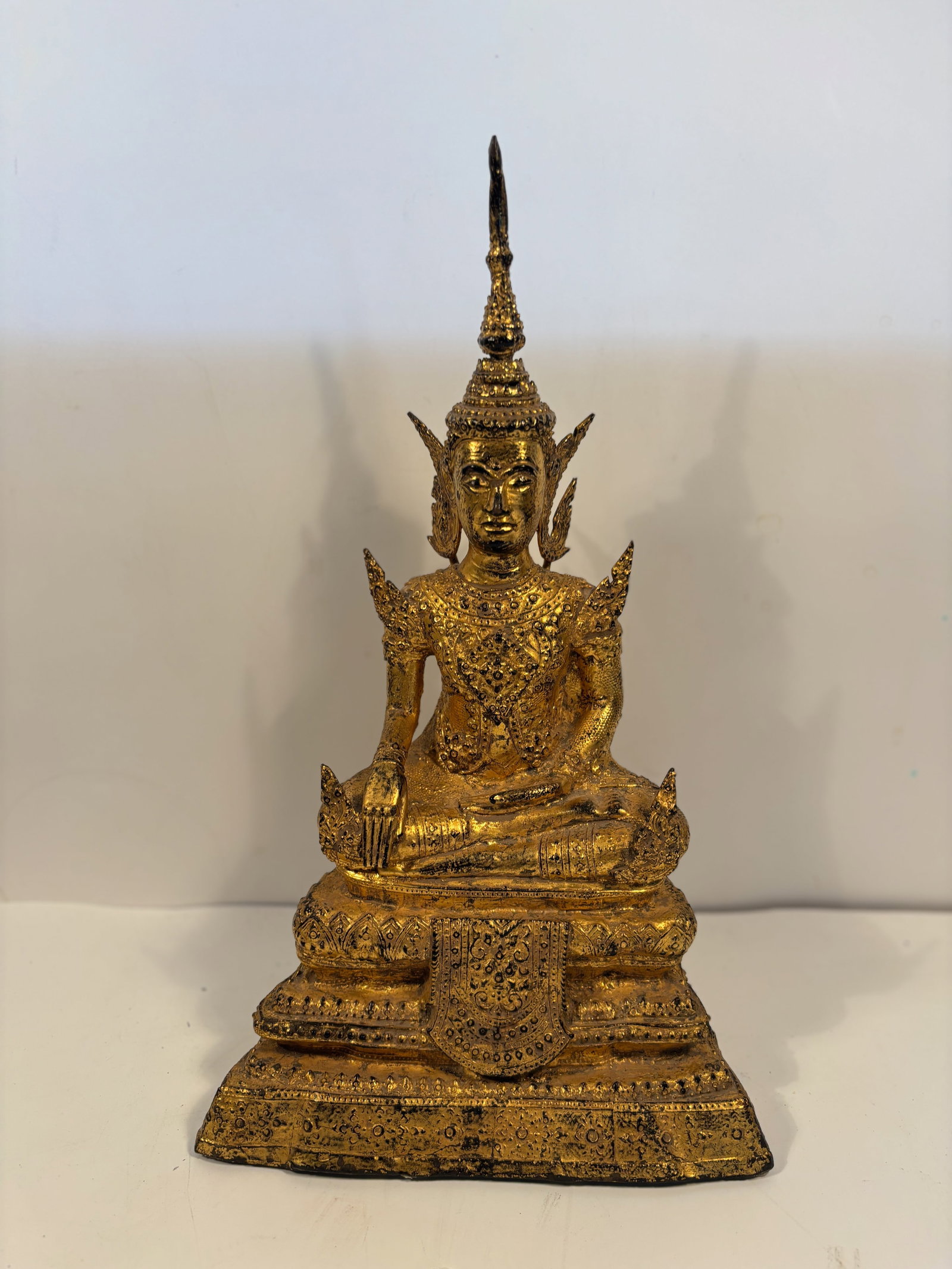 A Thai Gilt Bronze Buddha in Royal Attire, Rattanakosin Style: late 19th century, Royal Attire: the figure wears a highly ornate crown and jewelry, indicating a Buddha in royal costume (Phra Phuttha Chao Si Sawan style).Cast bronze, surface gilt with gold