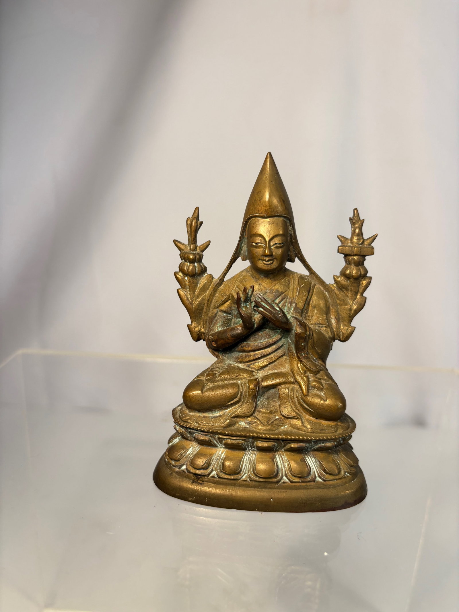 Gilt-Bronze Figure of Tsongkhapa, Tibet, 18th–19th Century: A finely cast gilt-bronze figure of Tsongkhapa, the revered founder of the Gelug (Yellow Hat) sect, shown seated in vajrasana on a double-lotus base. His hands are held in the dharmachakra mudra