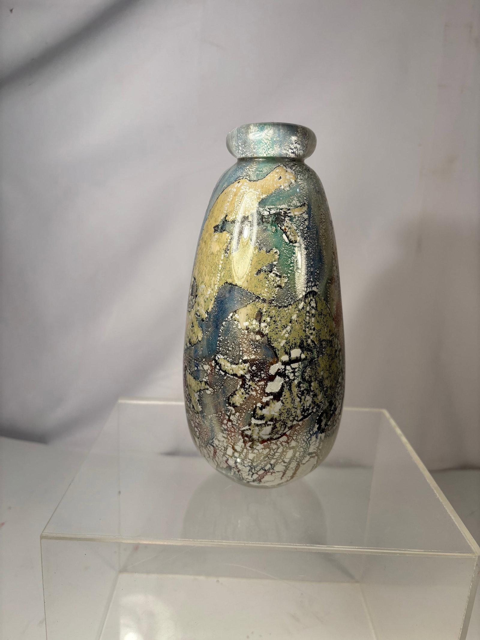 A Signed Studio Art Glass Vase, Abstract Mottled Decoration: A studio art glass vase of ovoid form with short flared neck, decorated with an abstract mottled surface in tones of blue, green, yellow, and earthy brown. The glass displays layered coloration with a