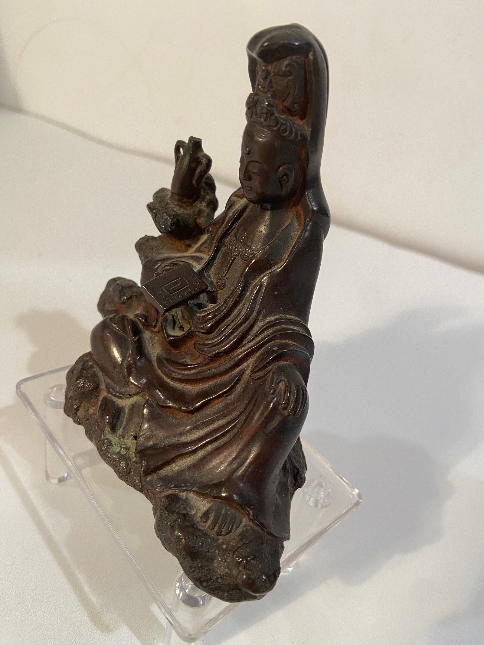 An Asian bronze Guanyin statue: 19th Century; The figure is seated on a naturalistic rocky base. The flowing robes and detailed adornments are typical of Guanyin or Buddhist figures. Dimensions?Height: 4 inches
