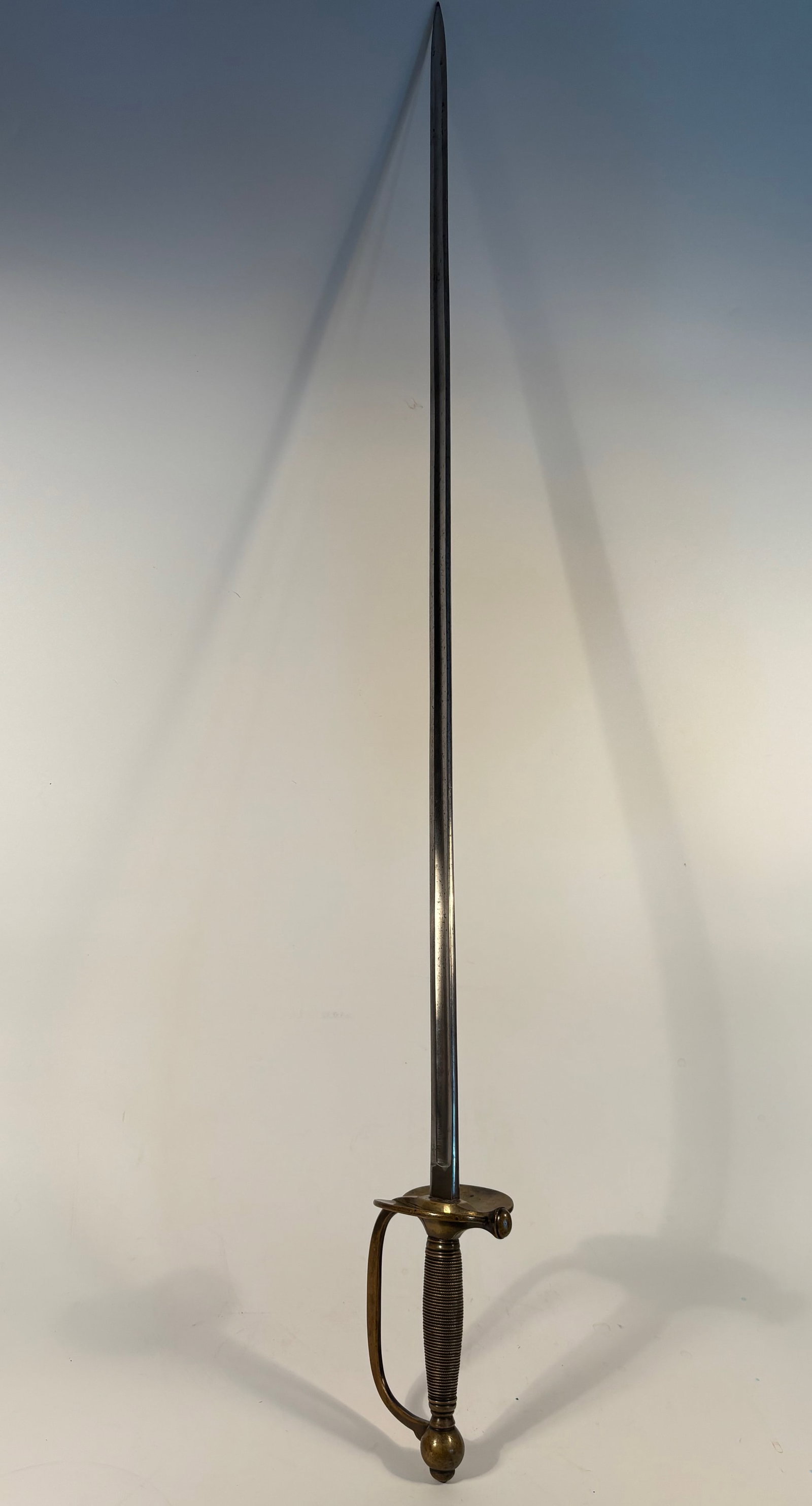 Officer’s Dress Sword with Brass Hilt and Wire-Wrapped Grip: Early 19th Century; Blade: Slim, straight, primarily designed for thrusting—not combat but ceremonial/military attire use; Hilt: Brass D-guard with a knuckle bow. Grip: Wire-wrapped (usually over a 