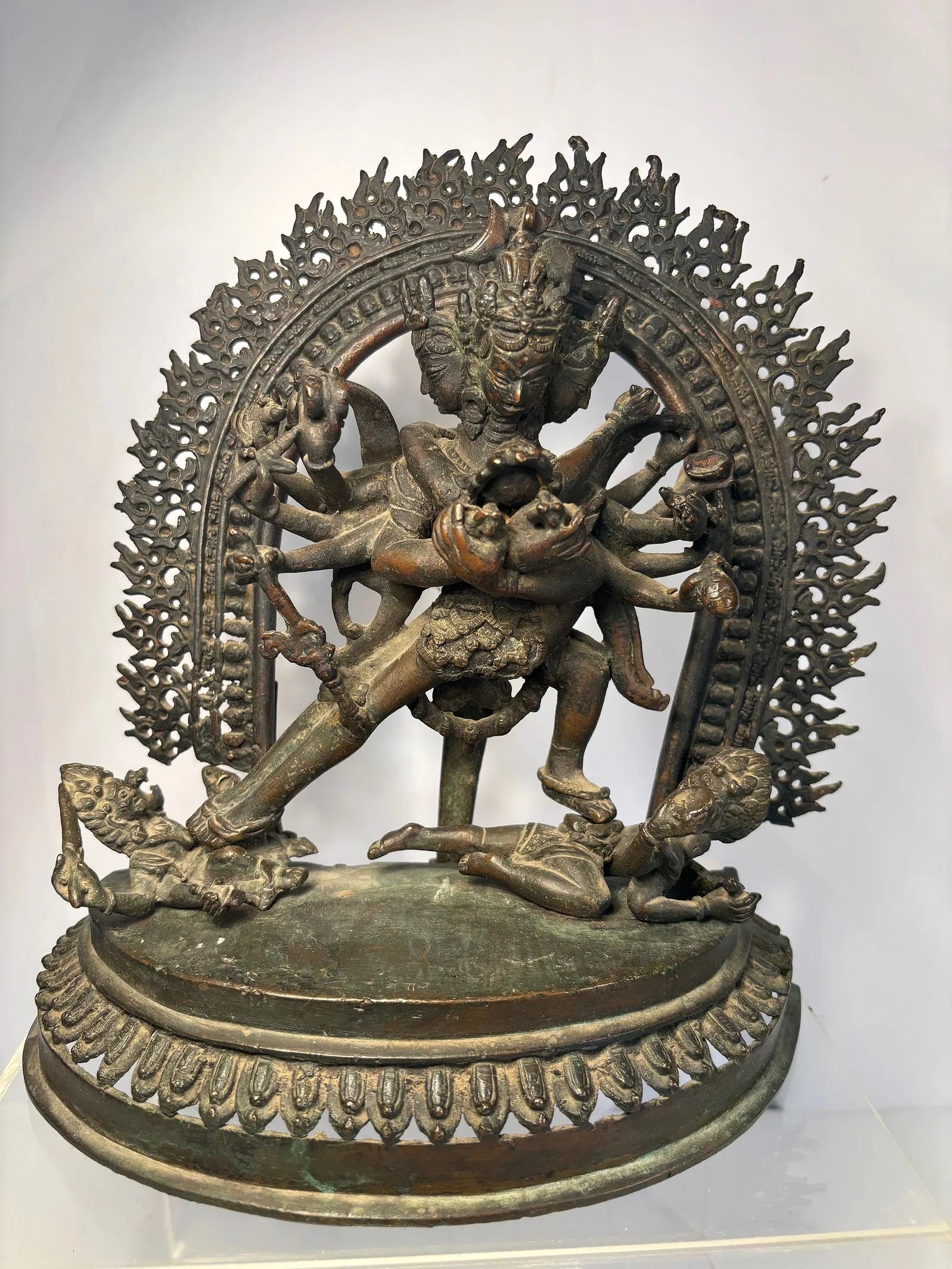 A Large Nepalese Bronze Statue of Chakrasamvara: 19th century : A large Nepalese cast bronze figure of the tantric deity Chakrasamvara in yab-yum with Vajrav?r?h?, surrounded by an elaborate flaming torana. The multi-armed deity stands atop a lotus 