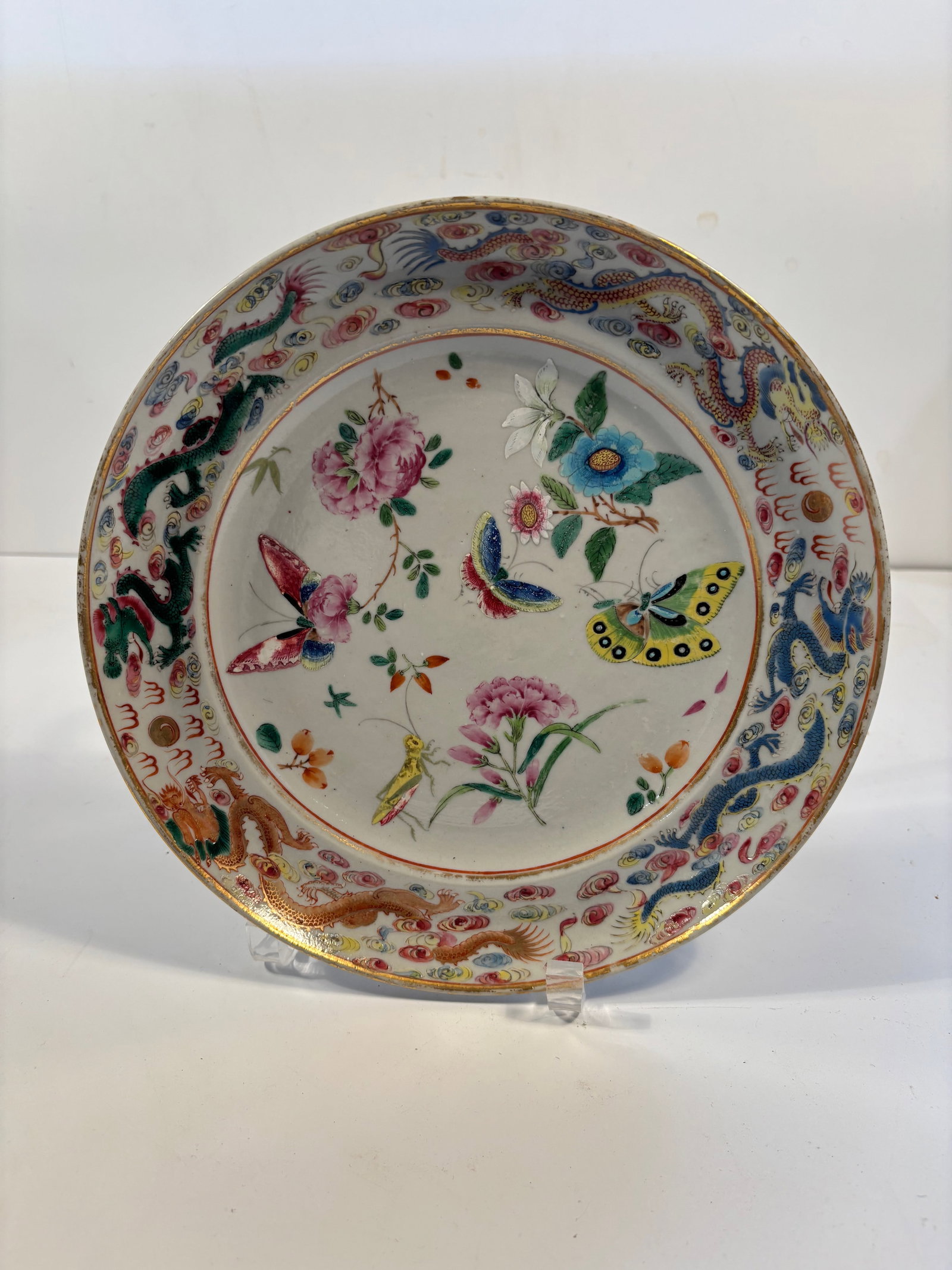 A Chinese famille rose porcelain round plate: Qing Dynasty (1644-1912), Features flowers, insects, and several large, vividly colored butterflies.Dimensions?10 inches; Height: 2 inches.